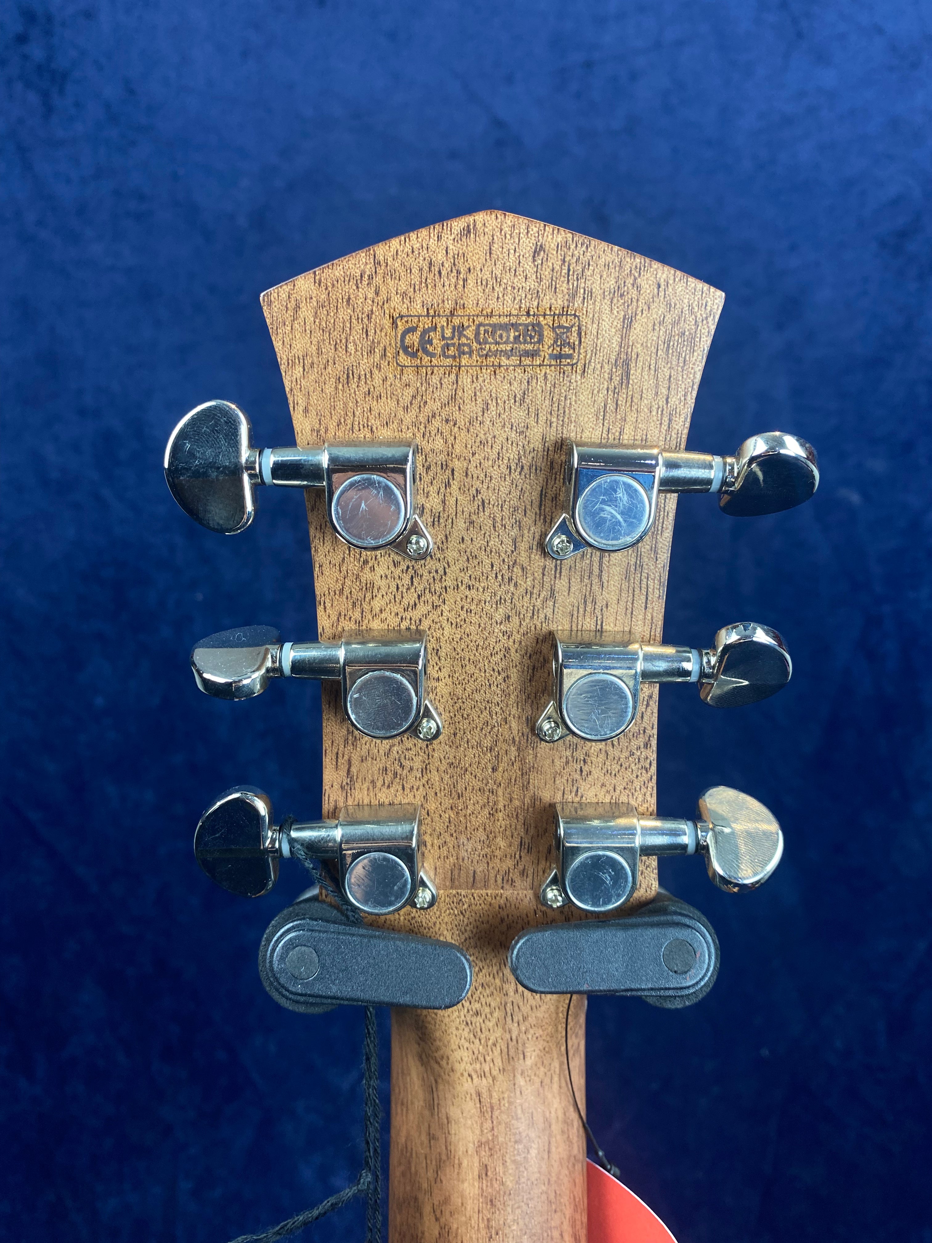 Six chrome tuning pegs on the back of a wooden acoustic guitar headstock, with a manufacturer's stamp and a black wall mount attached.