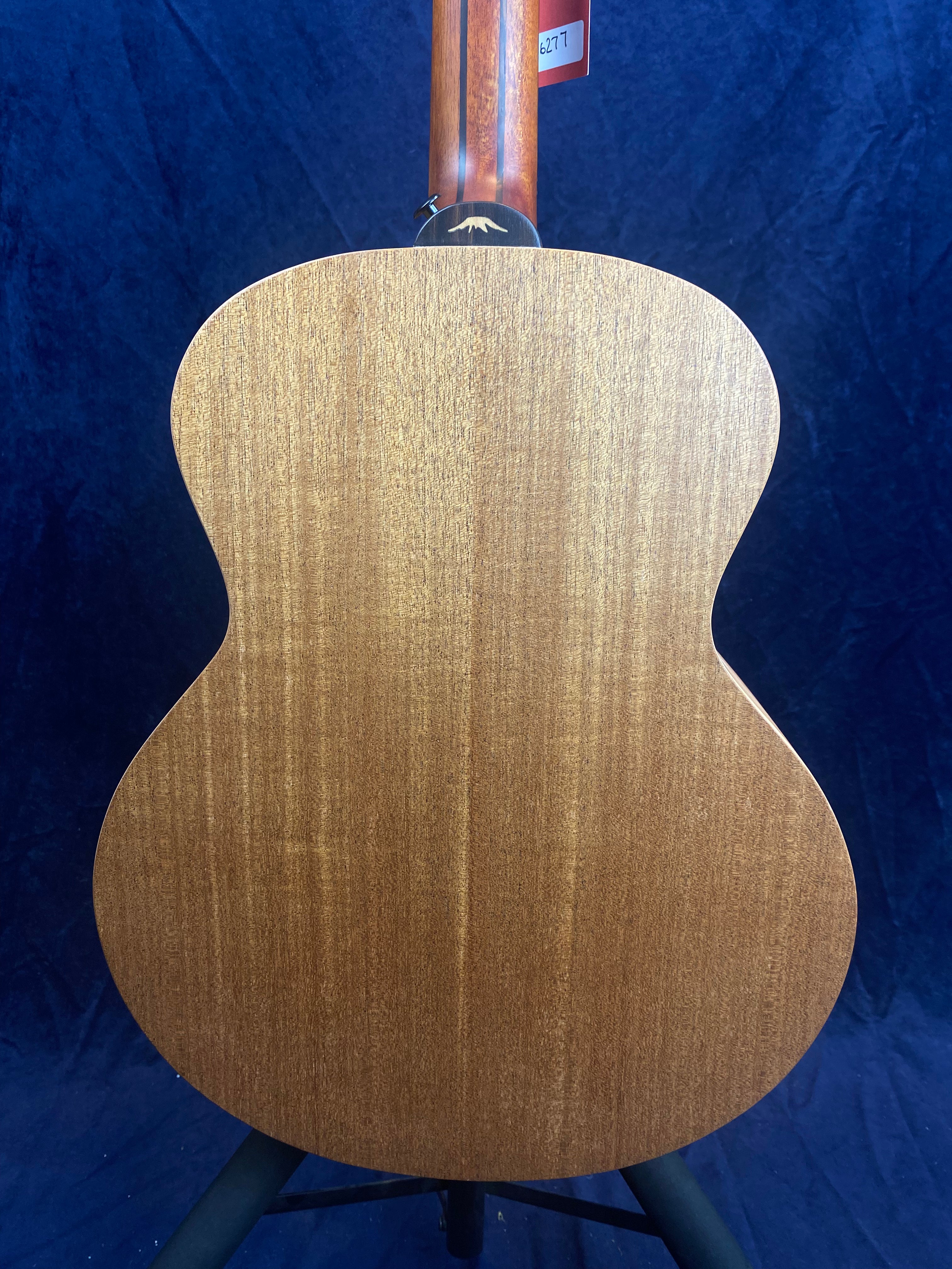 Rear view of an acoustic bass guitar made of smooth, medium brown wood with a curved body and visible grain patterns.