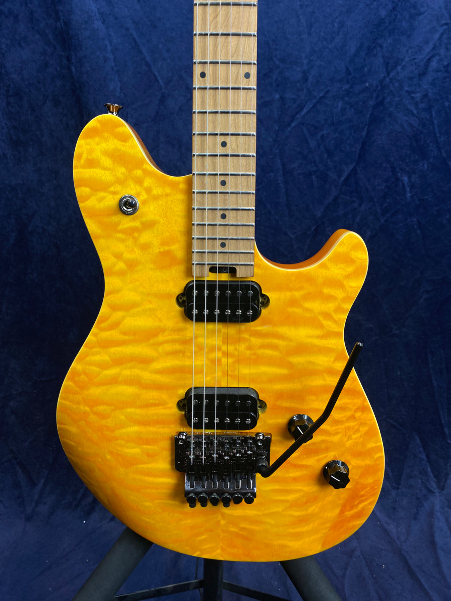 Electric guitar with a bright yellow quilted maple top, two black humbucker pickups, a tremolo bridge, and a maple fingerboard.