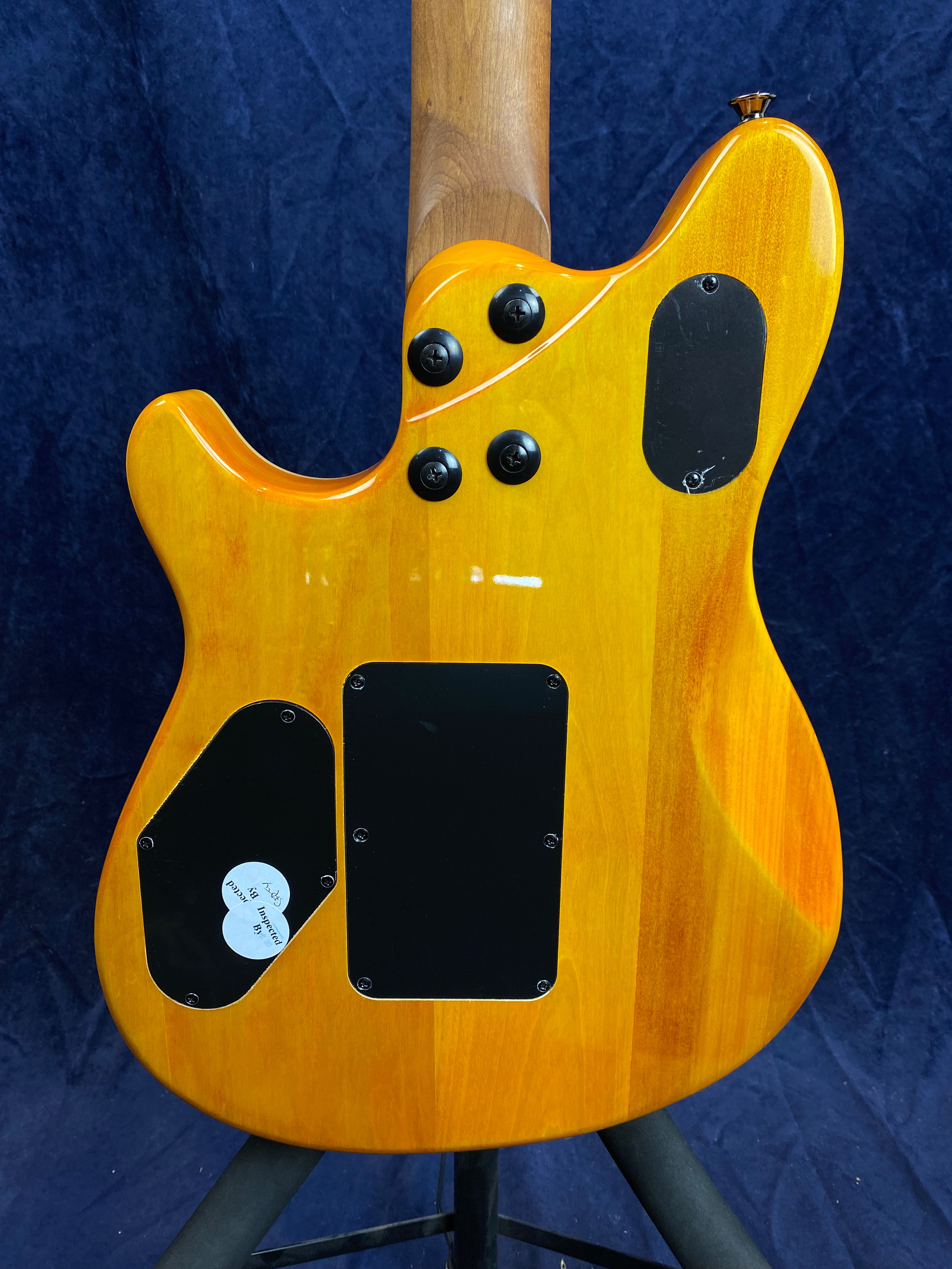 Back side of an electric guitar with a natural yellow glossy finish, three black access panels, four visible screw bolts, and a wood neck.
