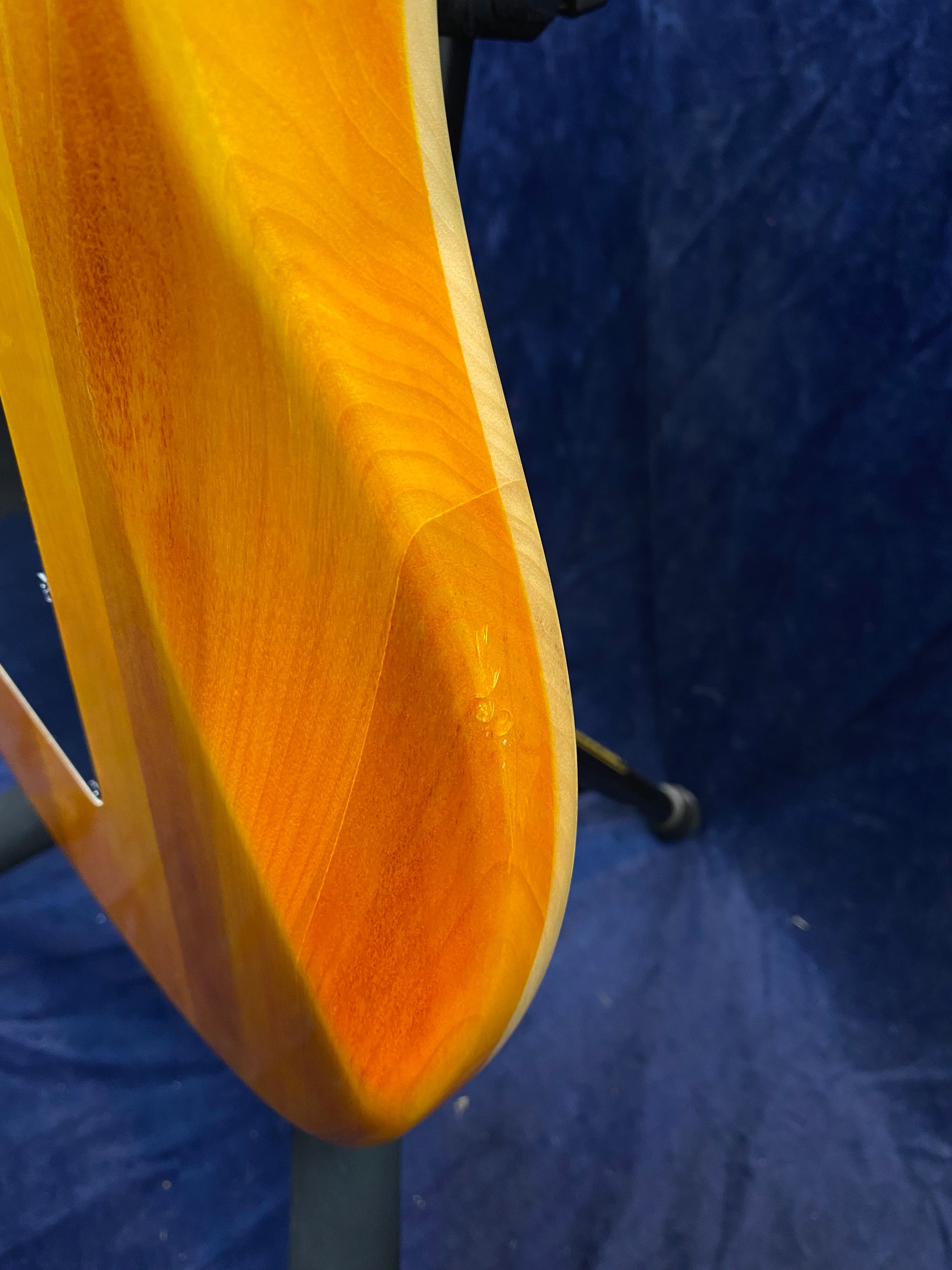 Close-up of a sunburst electric guitar body showing a small dent or ding in the wood near the bottom edge.