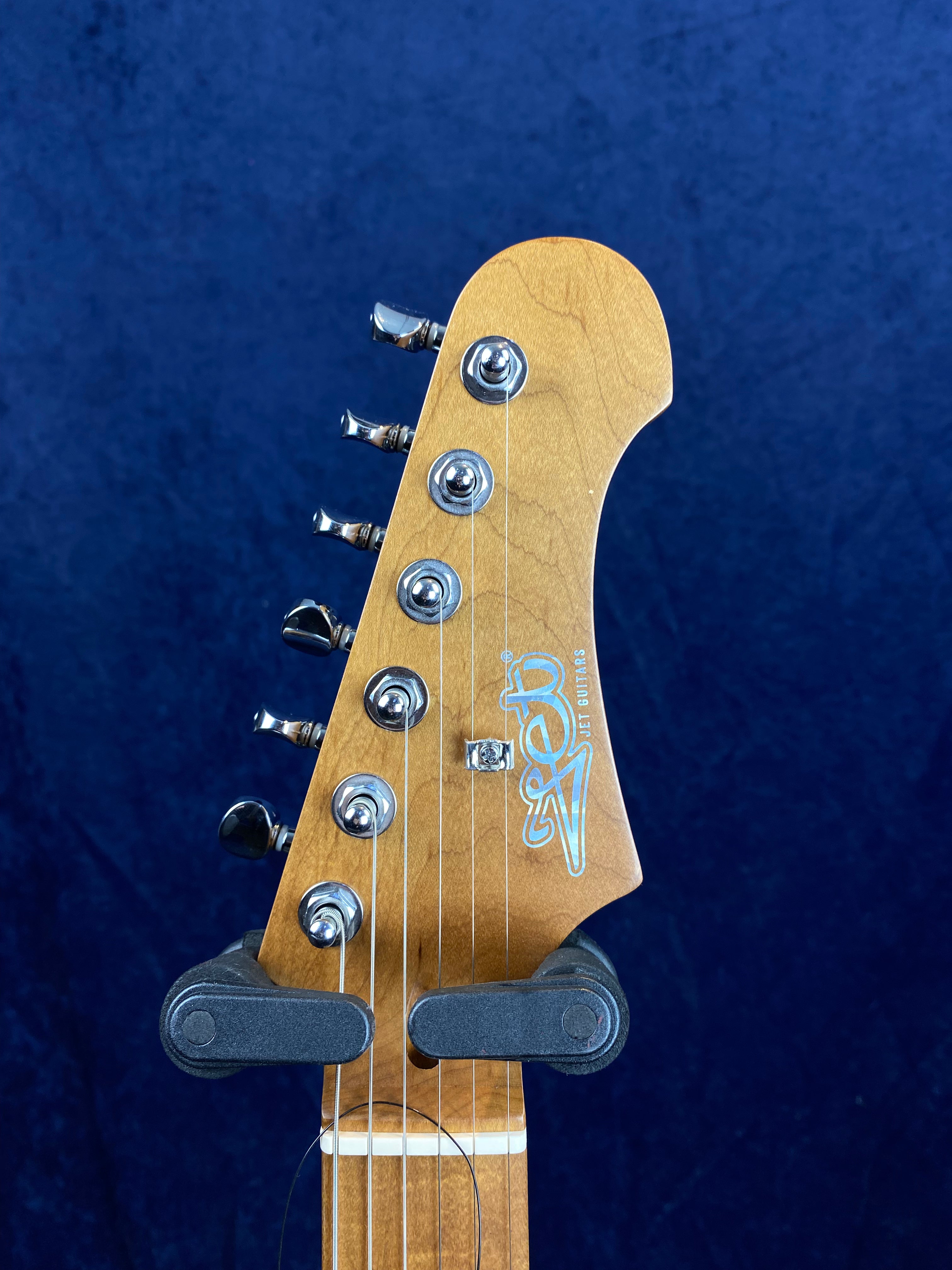 Electric guitar headstock with six tuning pegs, light wood finish, and "Jet Guitars" logo in blue on the front.