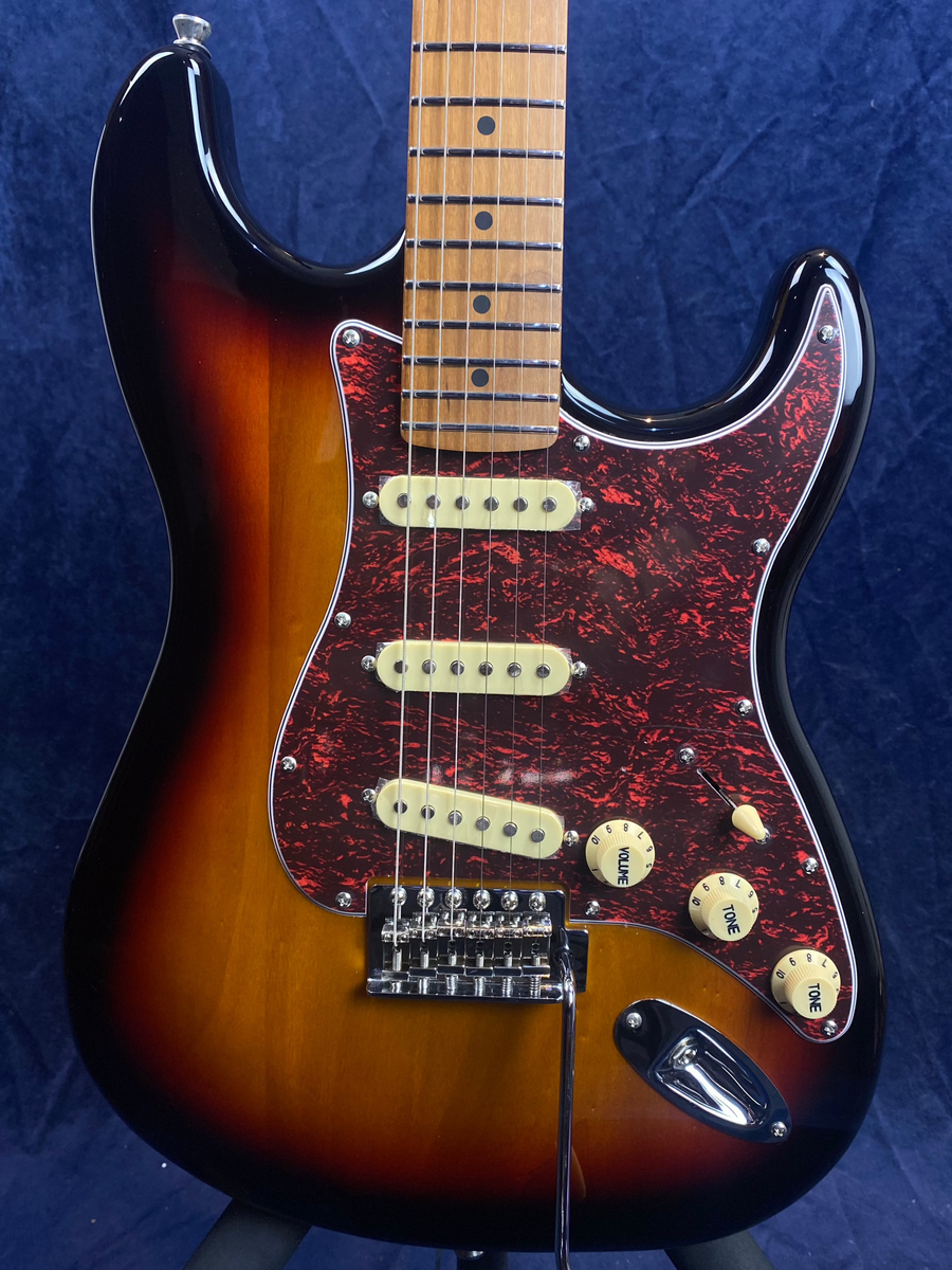 Sunburst electric guitar with a red marbled pickguard, three cream single-coil pickups, three control knobs, and a maple neck.