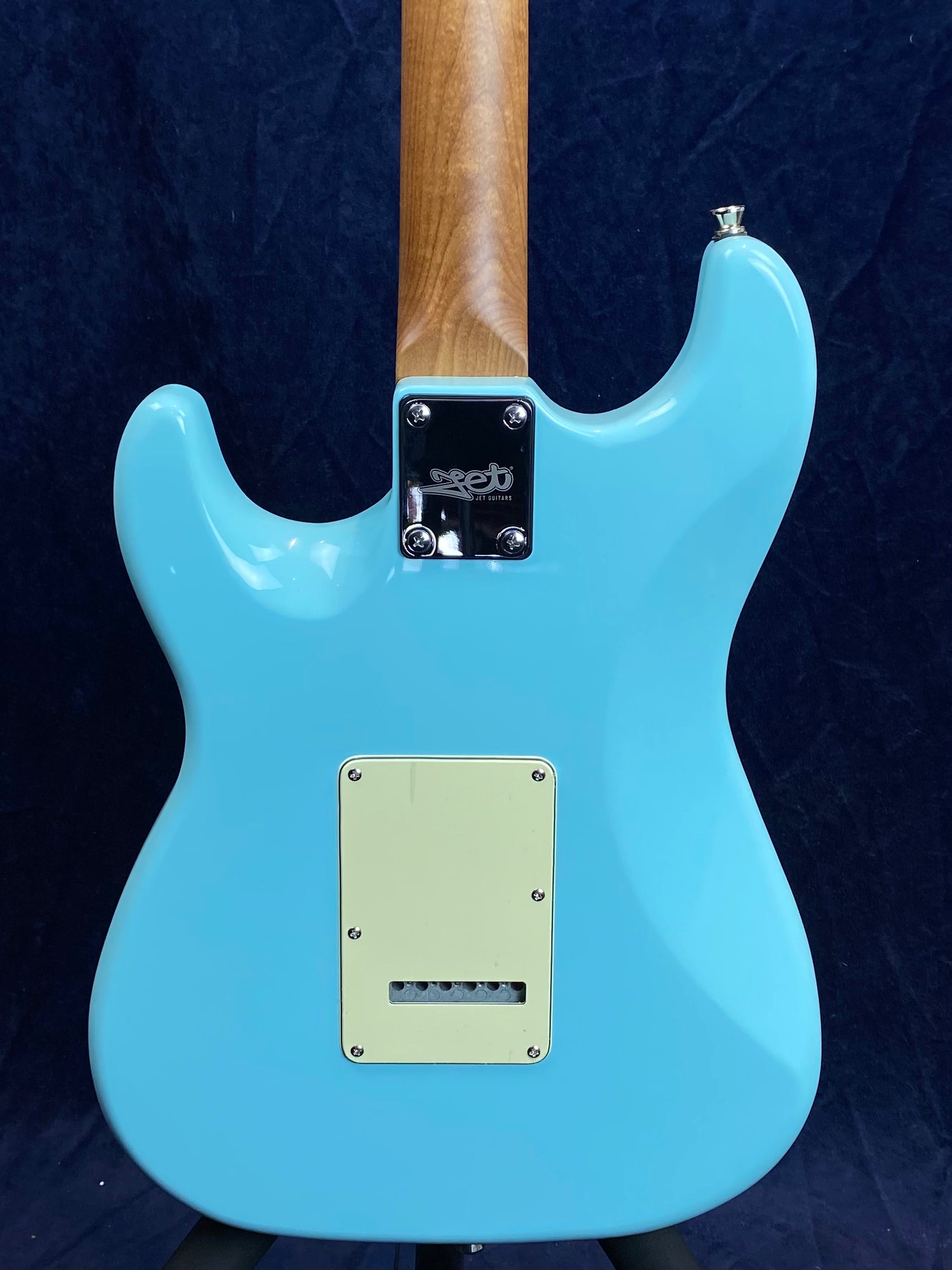 Light blue electric guitar body shown from the back, with a natural wood neck and a cream-colored rectangular backplate.