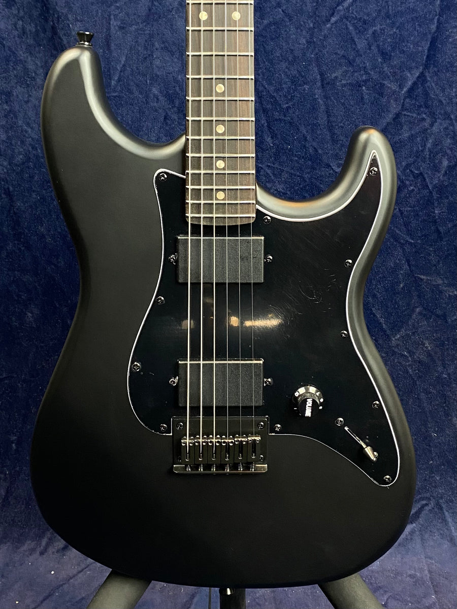 Black electric guitar with a matte finish, black pickguard, two rectangular pickups, single knob labeled "volume," and a toggle switch.