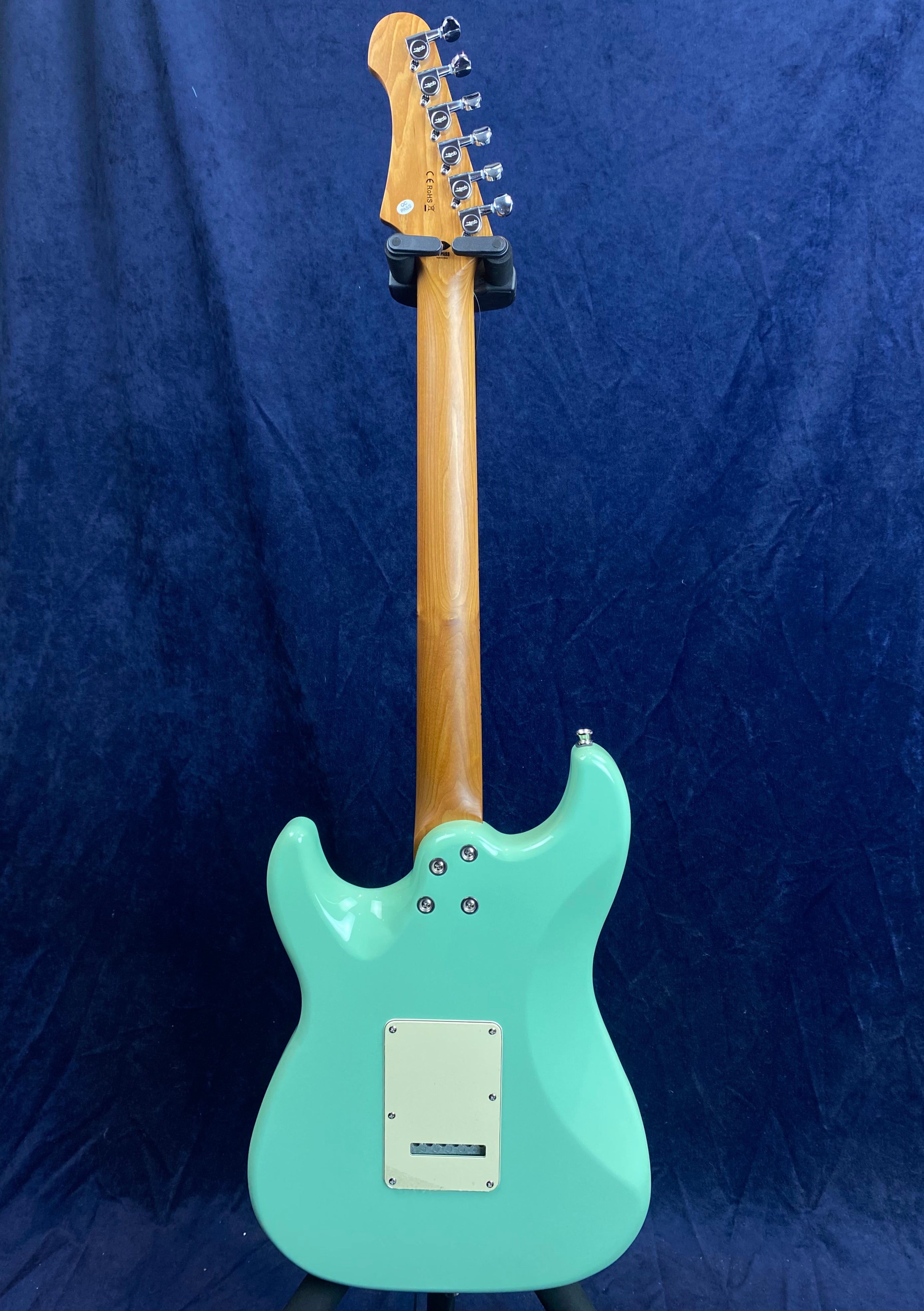 Guitare électrique vue de dos, corps vert menthe, manche en bois clair, plaque rectangulaire blanche fixée au dos du corps.