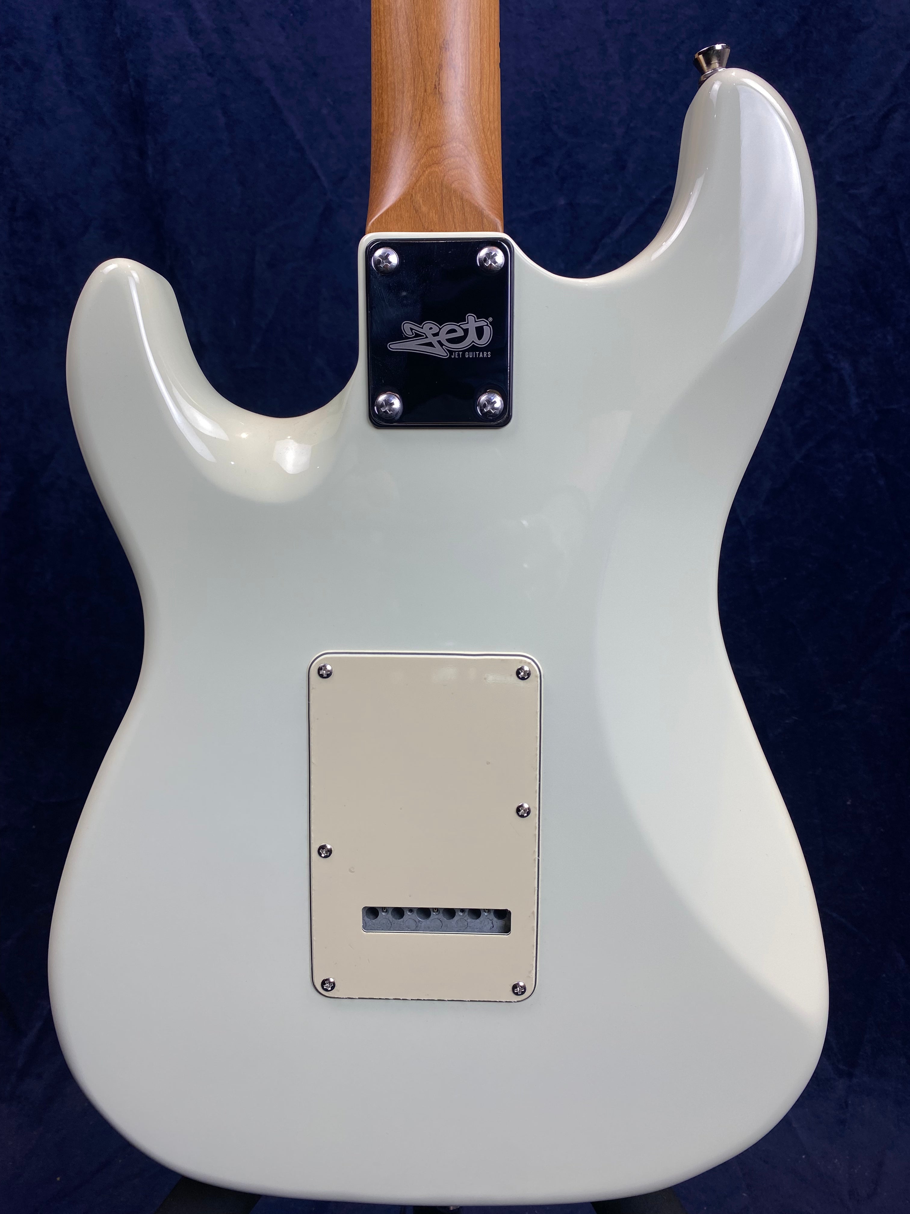 White electric guitar back showing a rectangular plastic cover for electronics and a neck plate labeled Jet Guitars, against a dark background.
