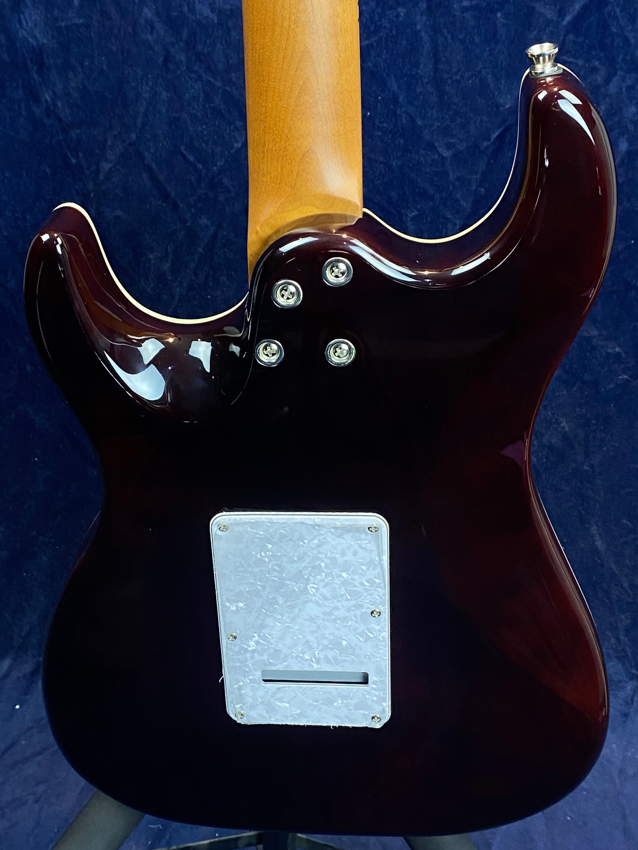 Glossy dark brown electric guitar back showing a light wood neck, four bolt neck joint, and a rectangular white plastic plate with a slot.