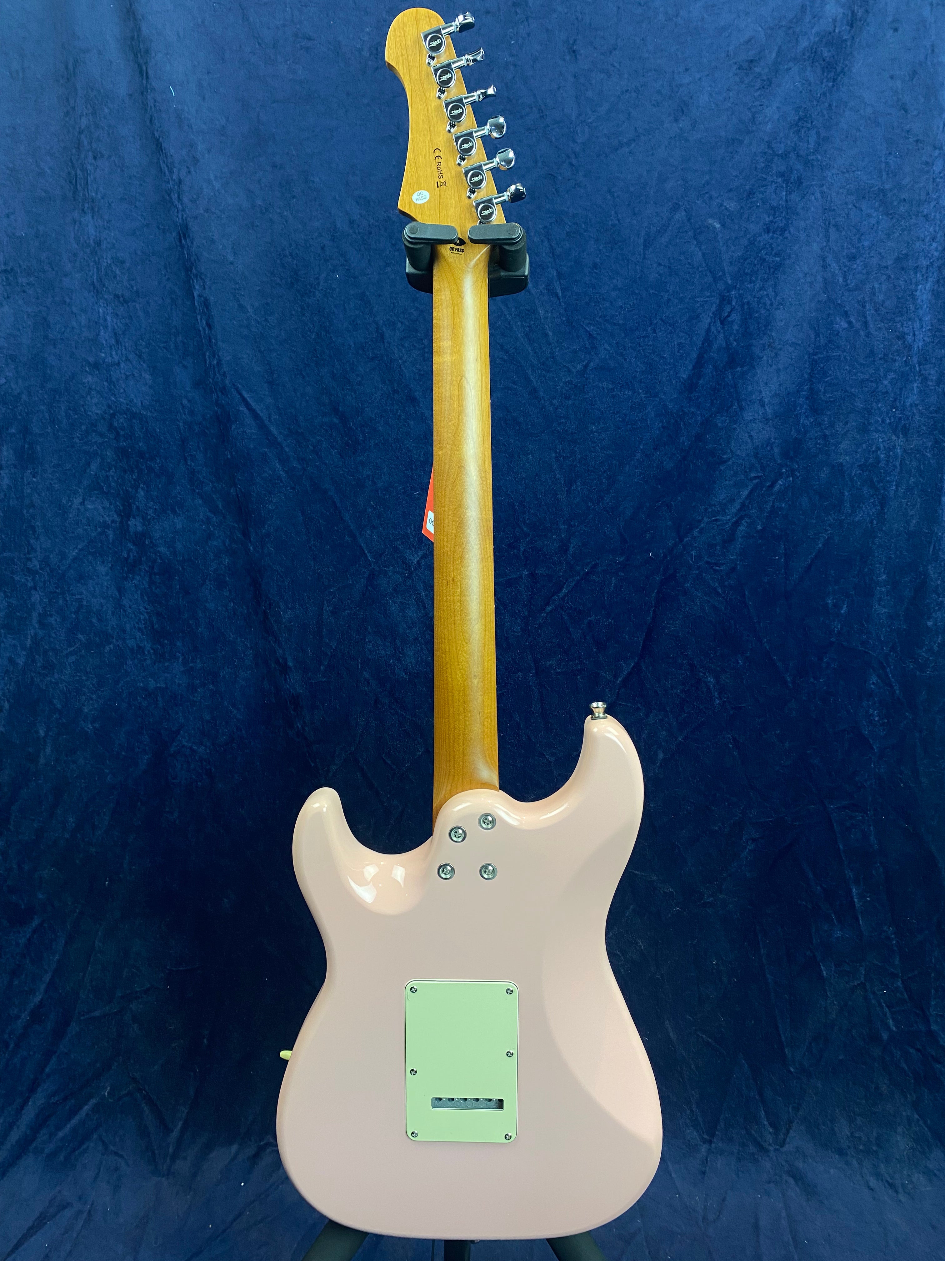 Light pink electric guitar shown from the back, with a natural wood neck, six tuning pegs, and a rectangular plastic cover on the body.