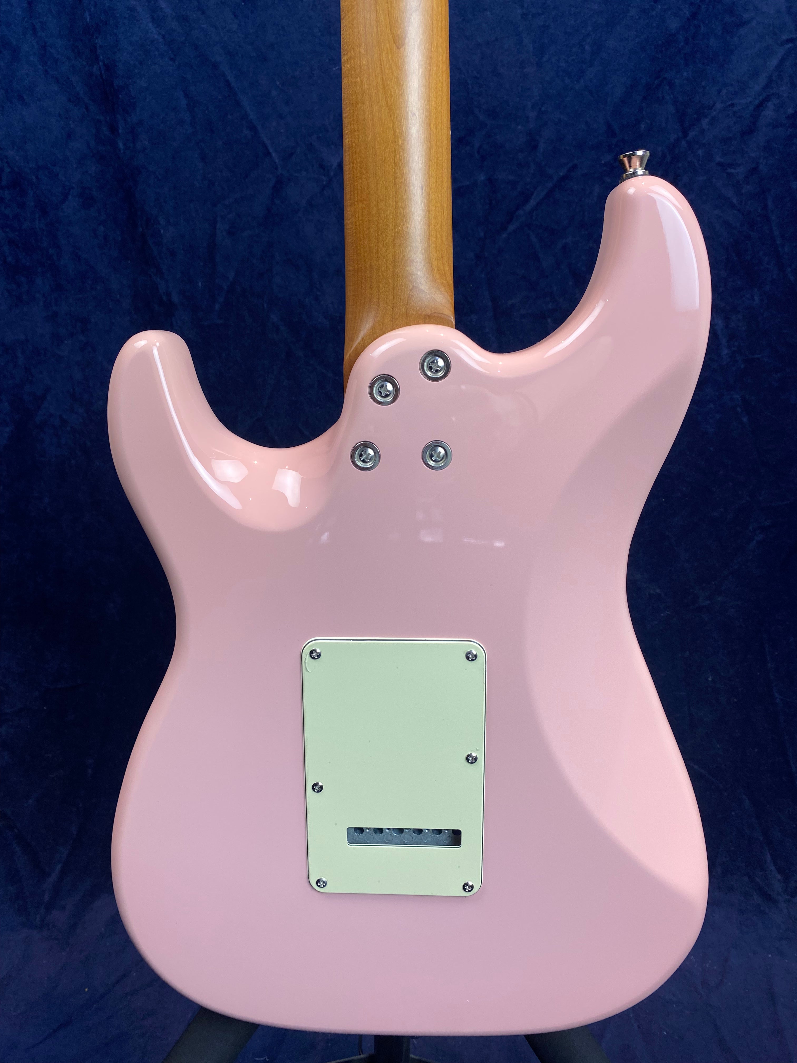Glossy light pink electric guitar back, natural wood neck, four neck screws, white rectangular back plate with six holes, dark blue background.