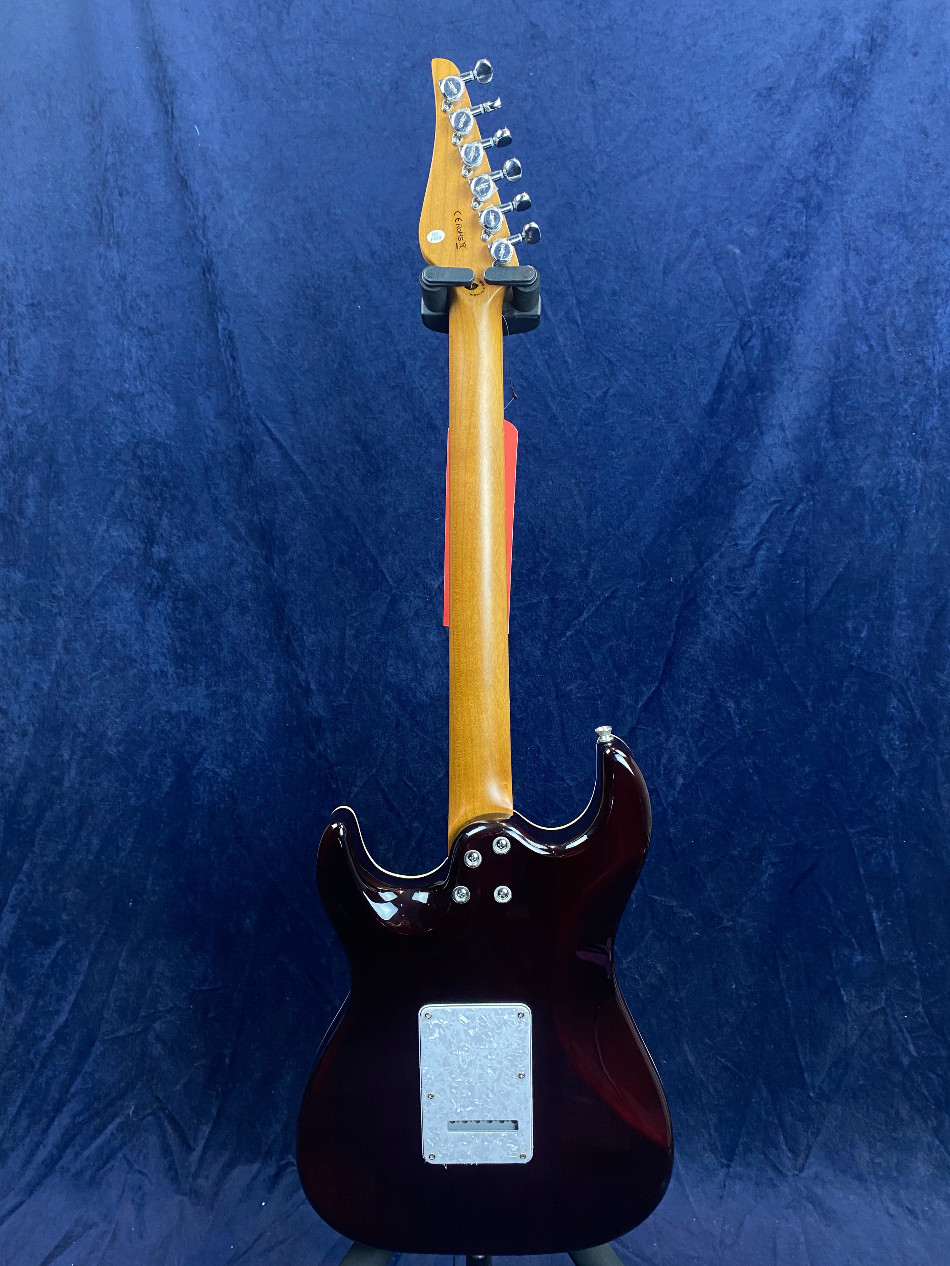 Electric guitar shown from the back, brown body with a light wood neck, six tuning pegs, and a rectangular cover plate near the base.
