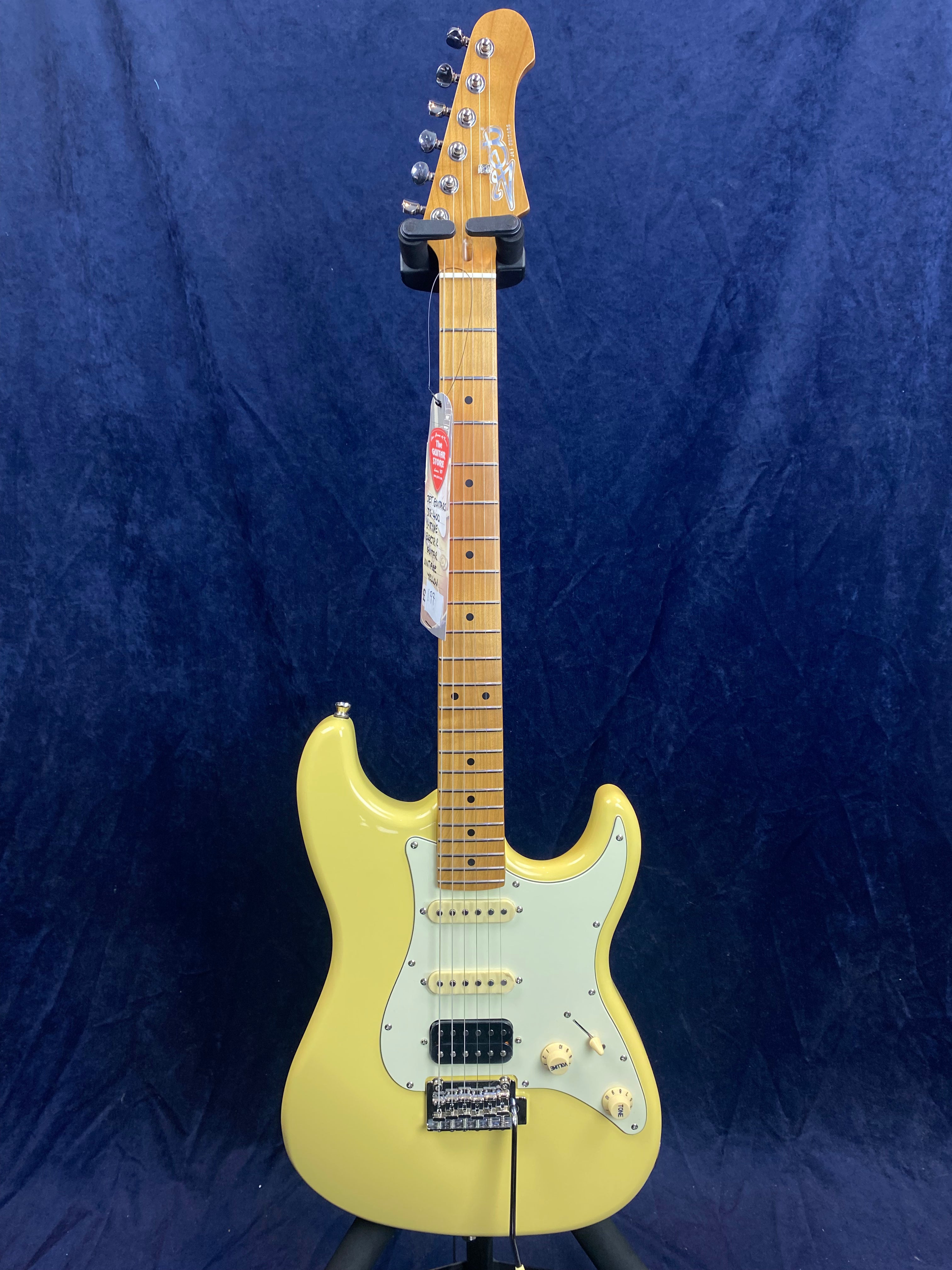 Yellow electric guitar with a light green pickguard, three pickups, and maple neck, shown upright against a dark blue background.