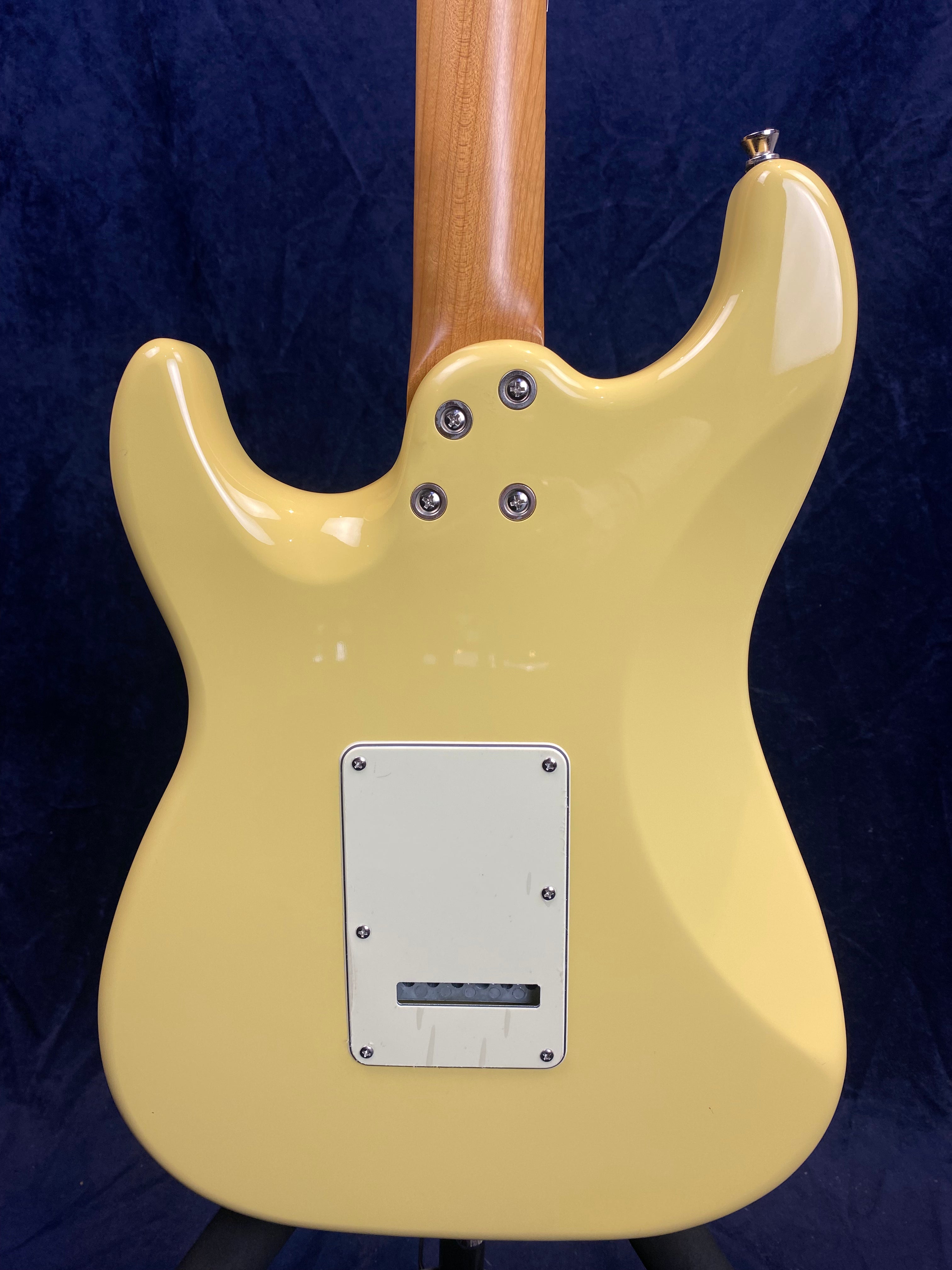 Yellow electric guitar back with a rectangular white cover plate secured by screws, four neck bolts, and a natural wood neck.