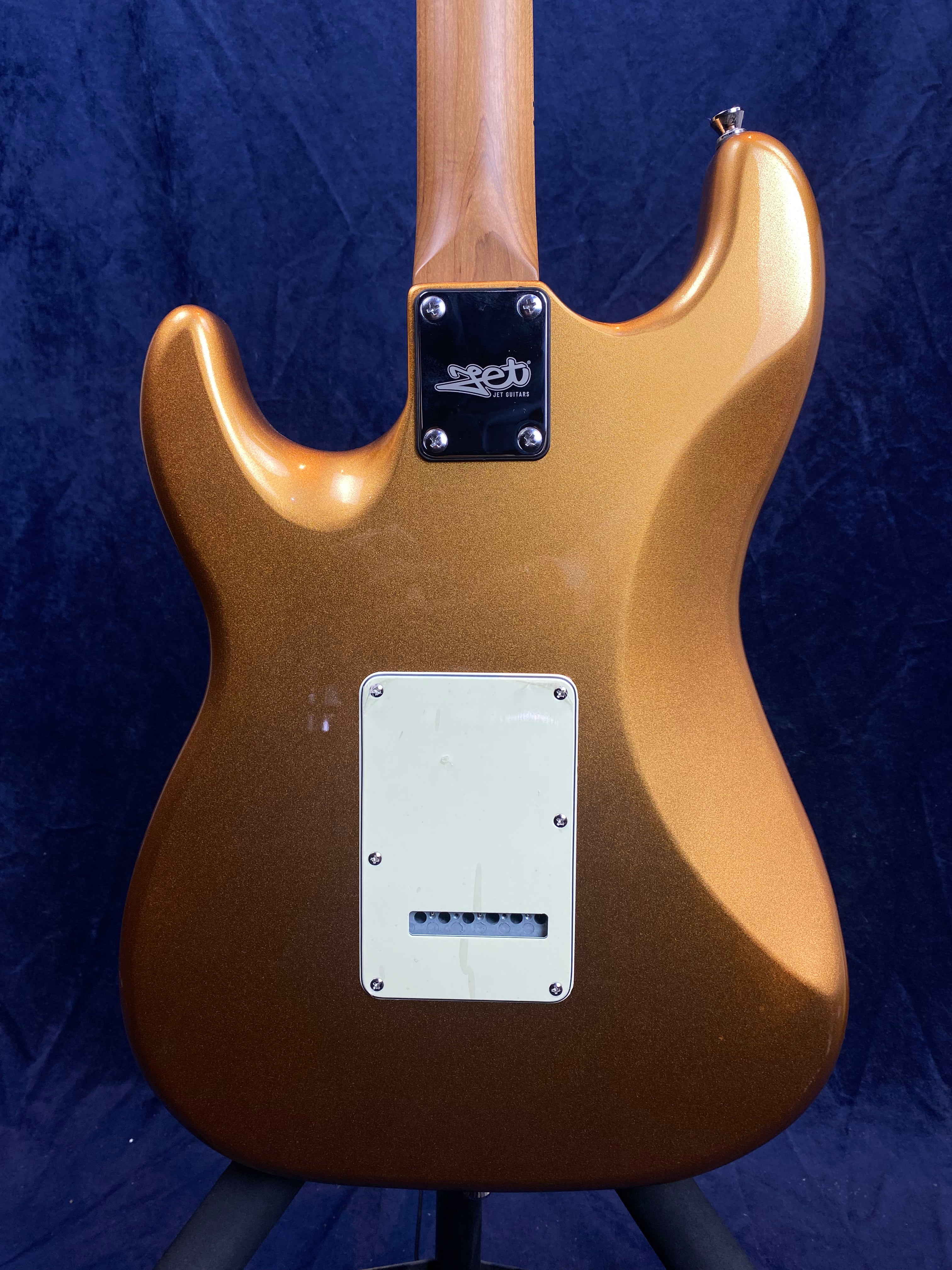 Metallic gold electric guitar back with a white rectangular plate and four-screw neck joint; neck is natural wood, body has contoured edges.