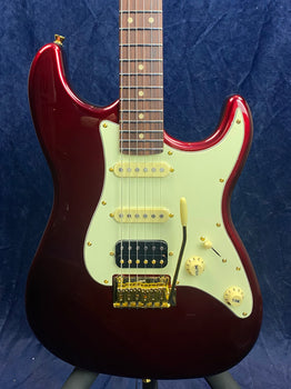 Metallic red electric guitar with a white pickguard, three pickups, gold hardware, and cream control knobs on a dark blue background.