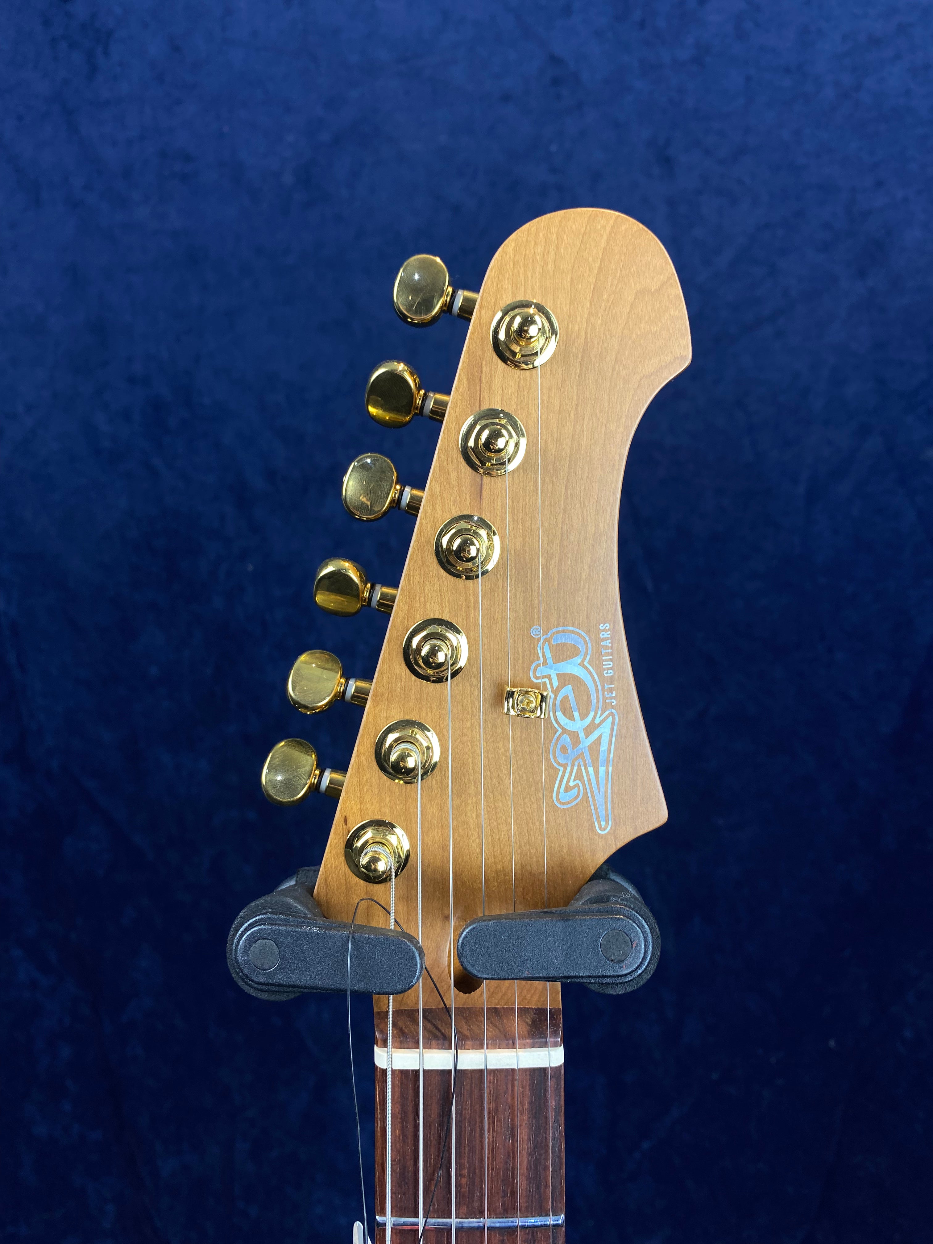 Electric guitar headstock with six gold tuning pegs, light wood finish, and the logo "SET GUITARS" in white lettering on the front.