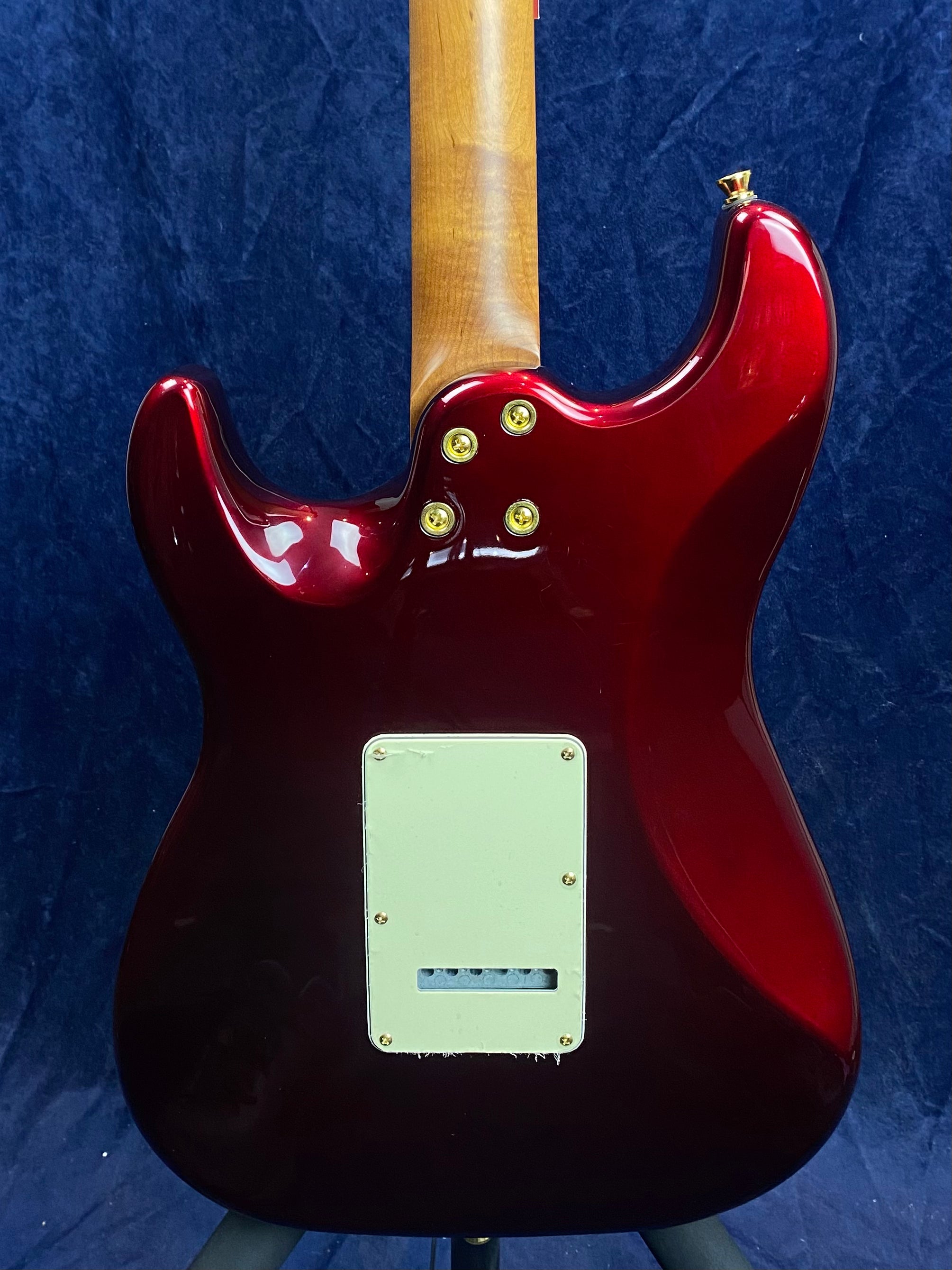 Glossy red electric guitar back, light wood neck, four gold neck bolts, and a white plastic cover plate near the bottom.