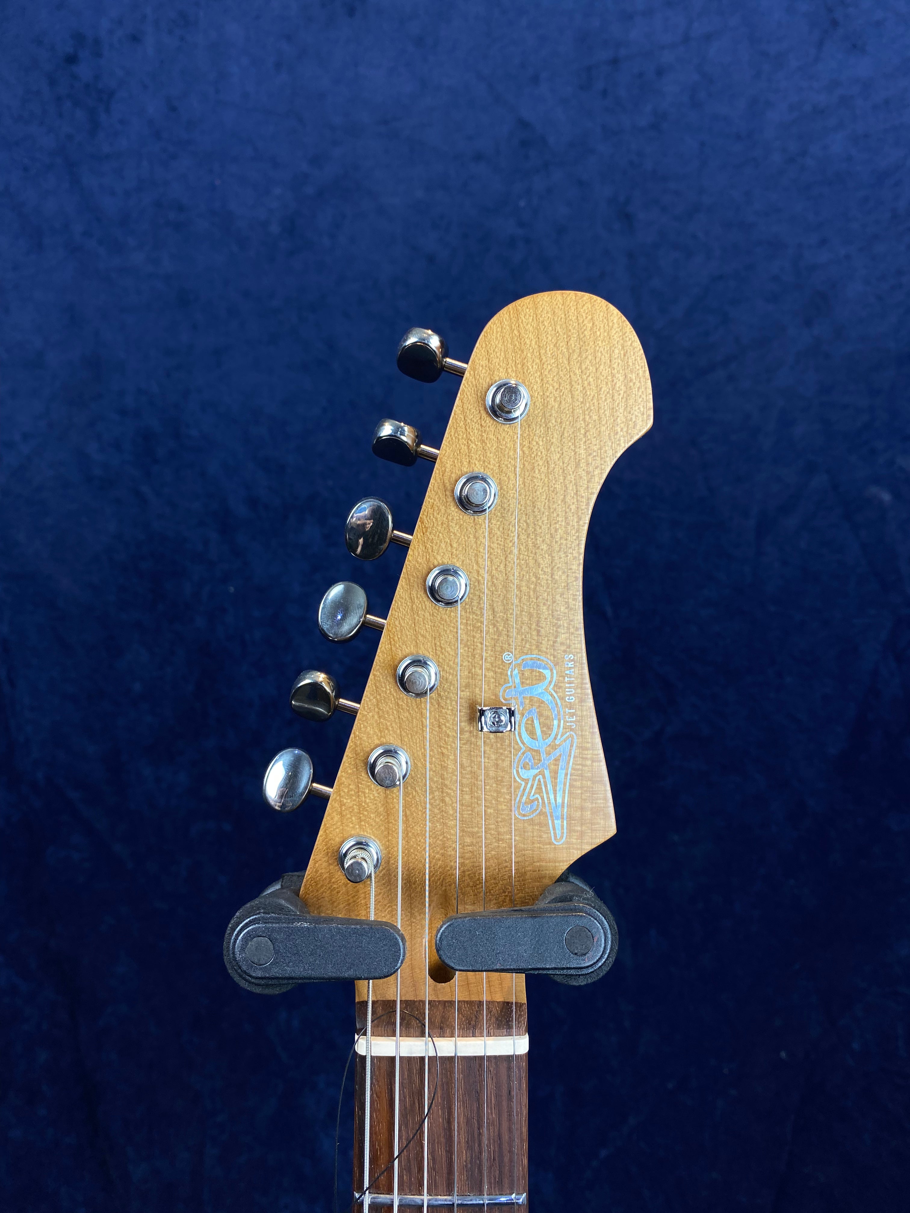 Electric guitar headstock with six chrome tuning pegs, maple wood finish, and a visible Joe Collins signature logo in white.