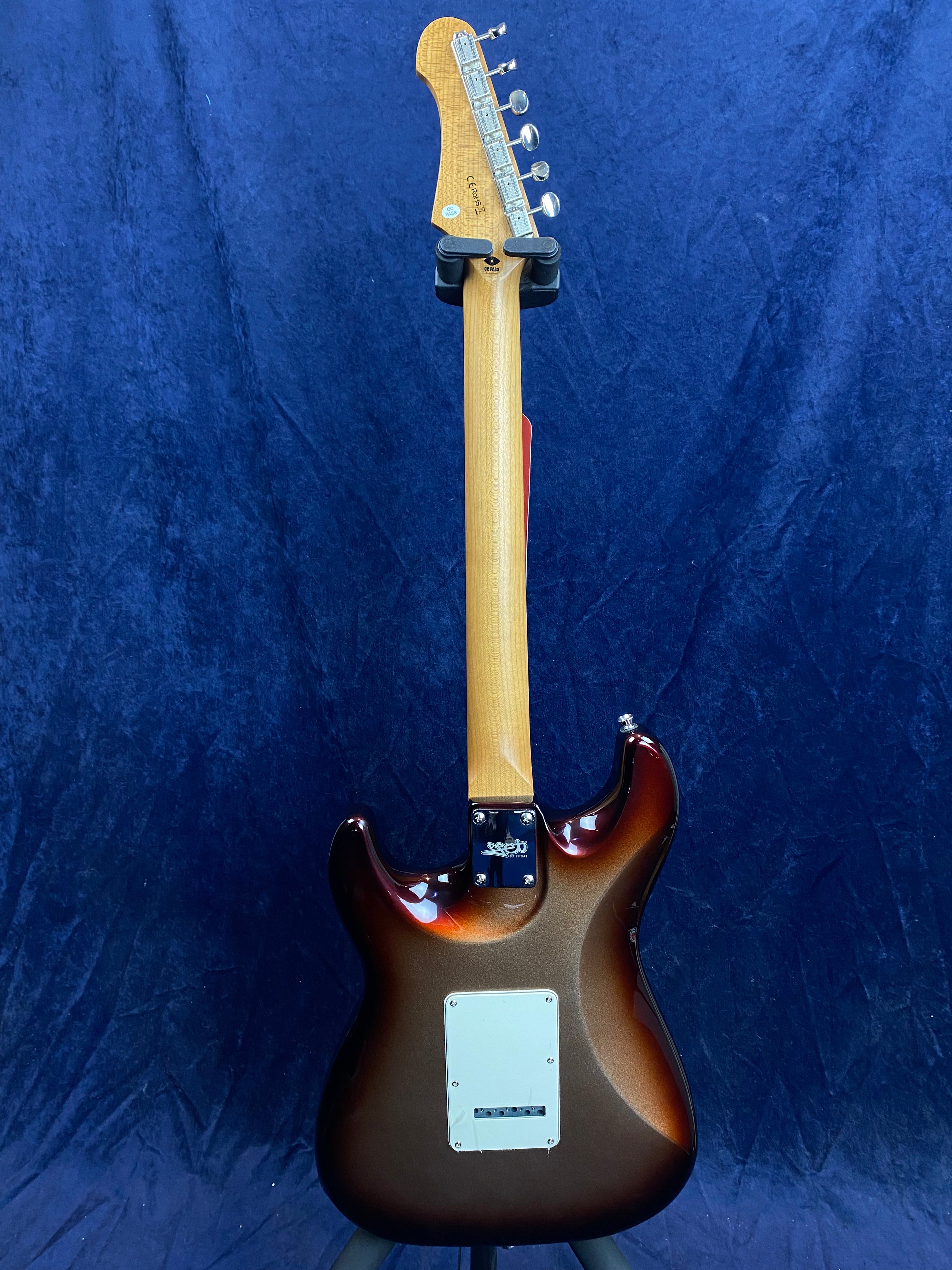 Electric guitar shown from the back, sunburst brown body, natural wood neck, six tuning pegs on the headstock, white back plate, blue background.