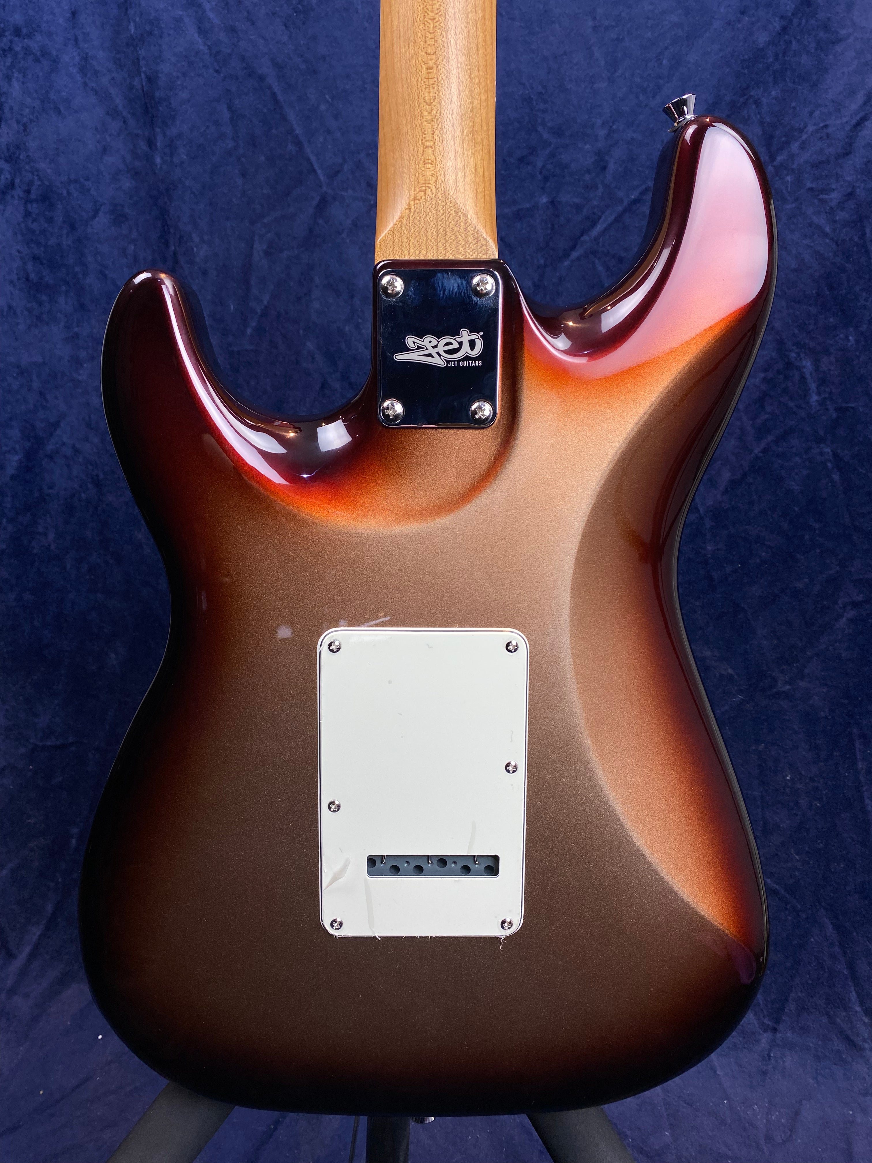 Sunburst finish electric guitar back with a white rectangular cover plate and neck joint plate labeled "JET Guitars" against a dark background.