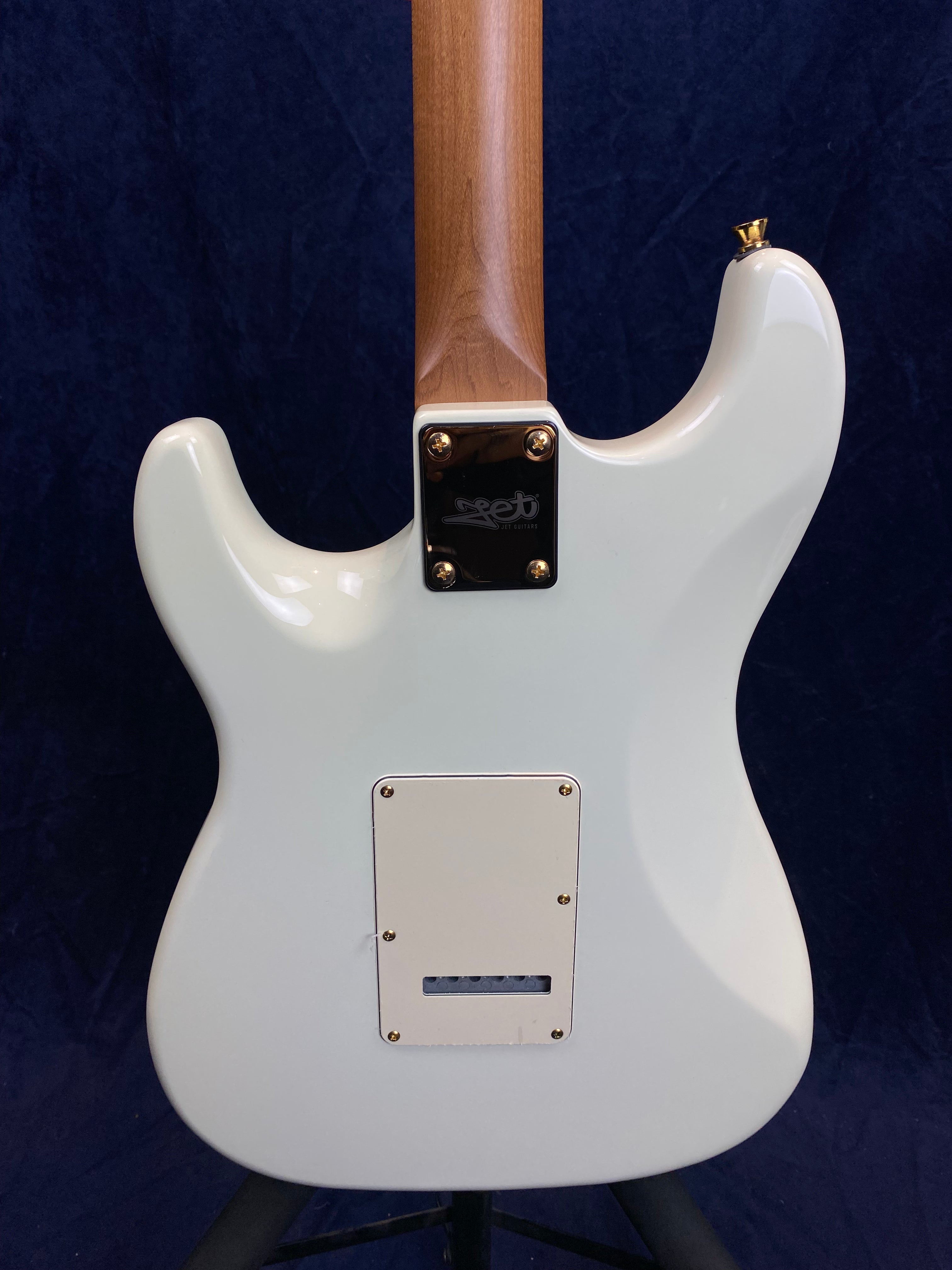 White electric guitar body and natural wood neck, shown from the back, with a rectangular cover plate and four screws securing the neck plate.