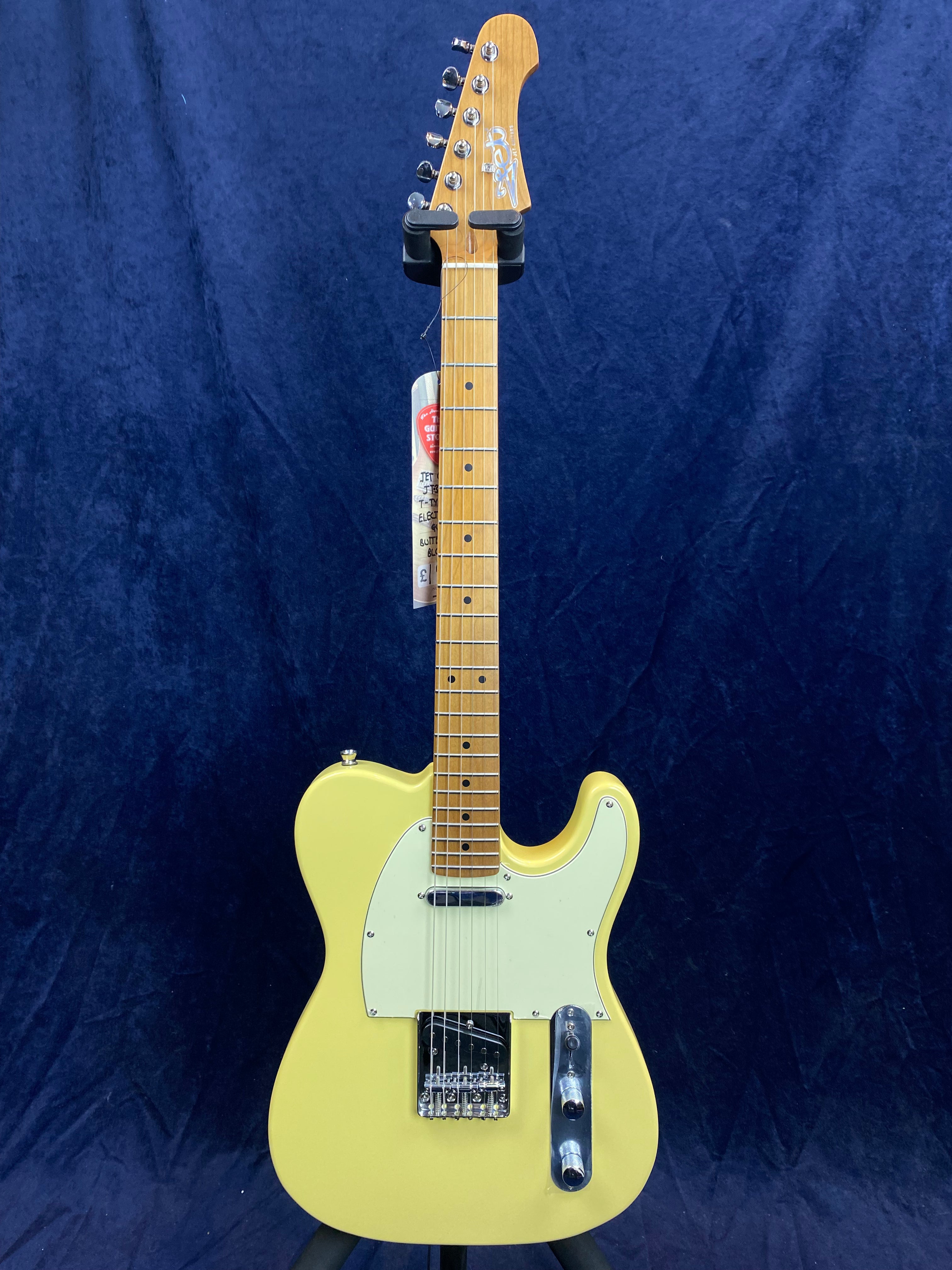 Yellow electric guitar with a single-cutaway body, maple neck, white pickguard, two control knobs, and chrome hardware, displayed against a dark background.
