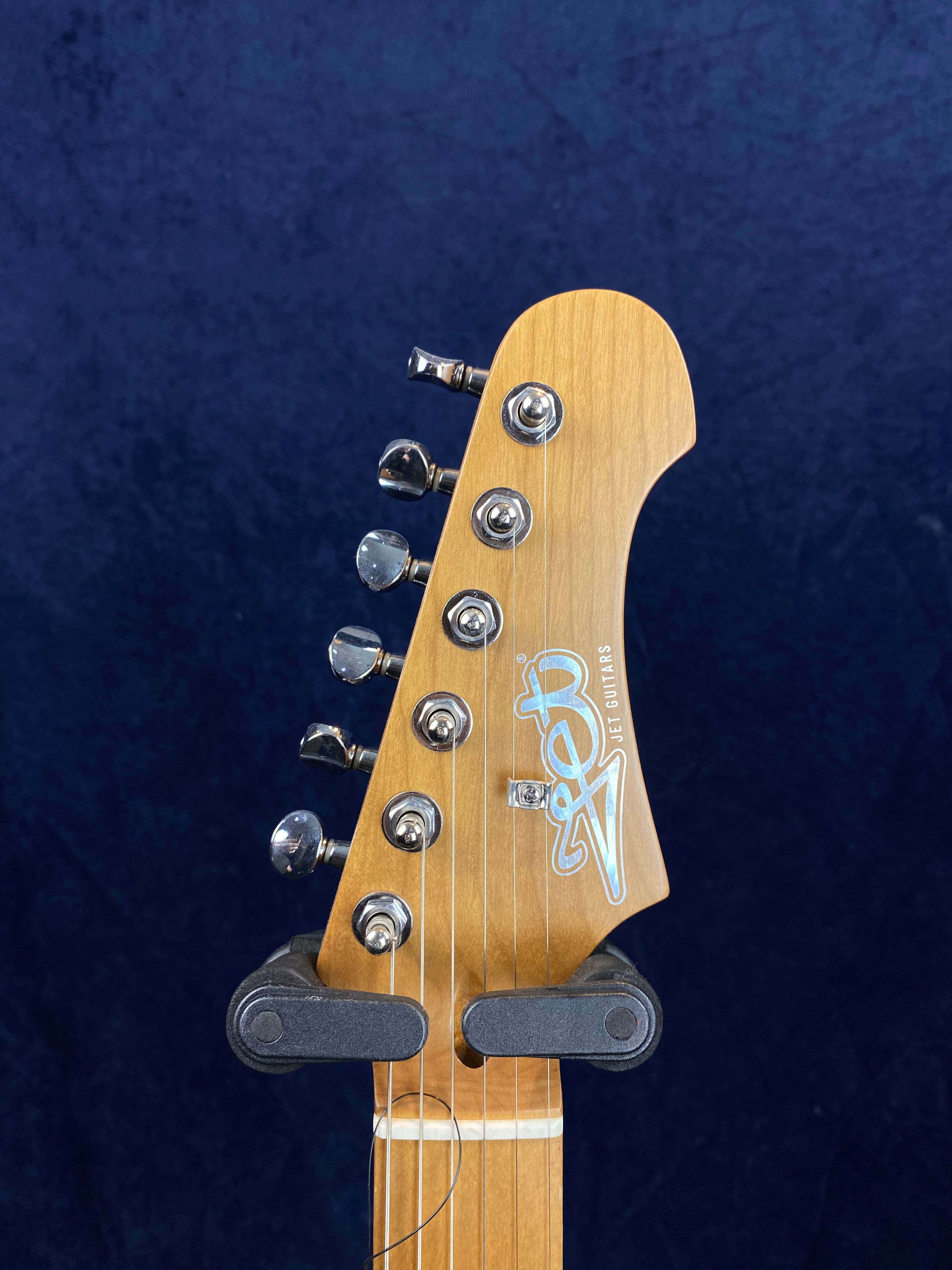 Light wood electric guitar headstock with six silver tuning pegs and "Jet Guitars" logo in blue and white.
