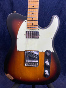 Electric guitar with a sunburst finish, white pickguard, two pickups, chrome bridge, and two control knobs on a metal plate. Some visible scratches.