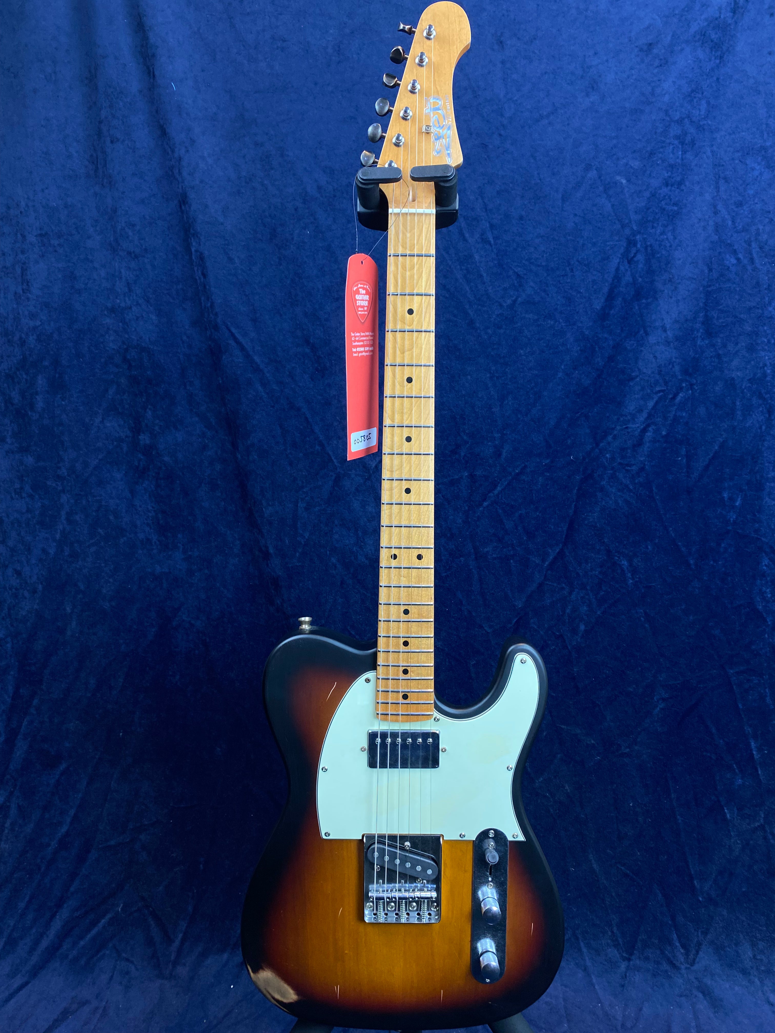 Sunburst electric guitar with light wood neck, white pickguard, two pickups, and chrome hardware, displayed upright against a dark blue background.