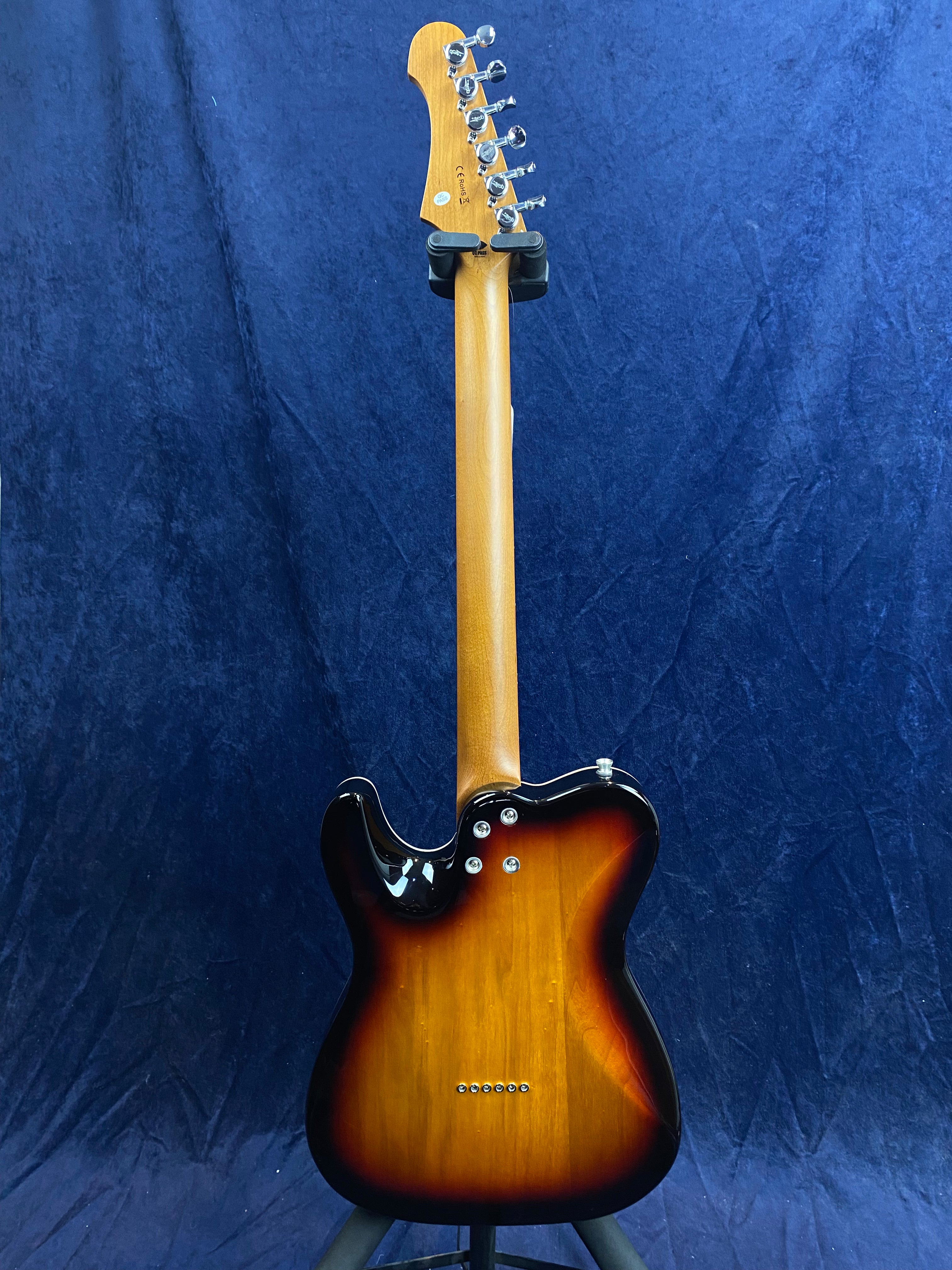 Sunburst electric guitar shown from the back, displaying a maple neck, chrome tuners, and a glossy, contoured body with black and brown finish.