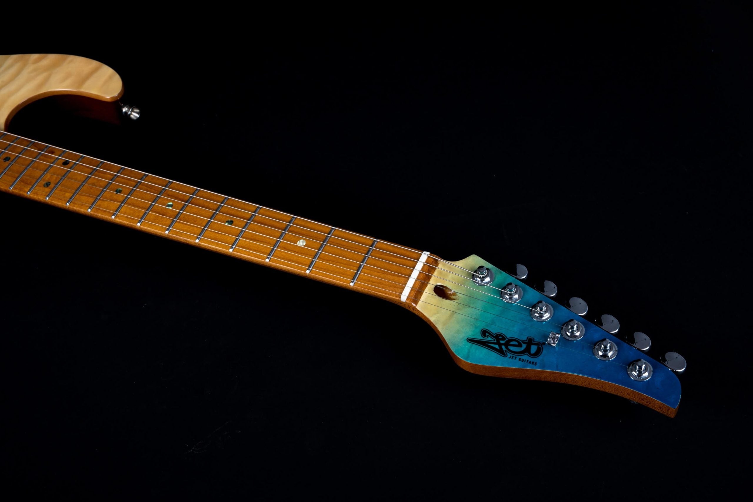 Electric guitar neck with a glossy wood finish, chrome tuning pegs, and a blue-to-green gradient headstock marked with the Jet Guitars logo.
