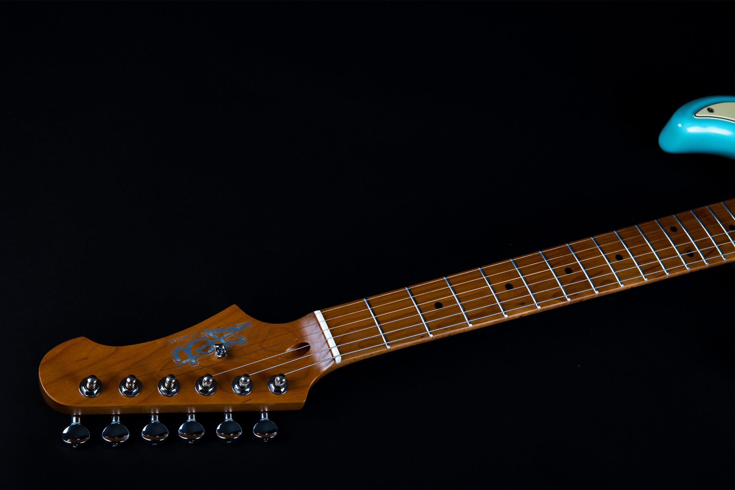 Light brown electric guitar neck and headstock with six tuning pegs, turquoise guitar body partially visible on the right, black background.