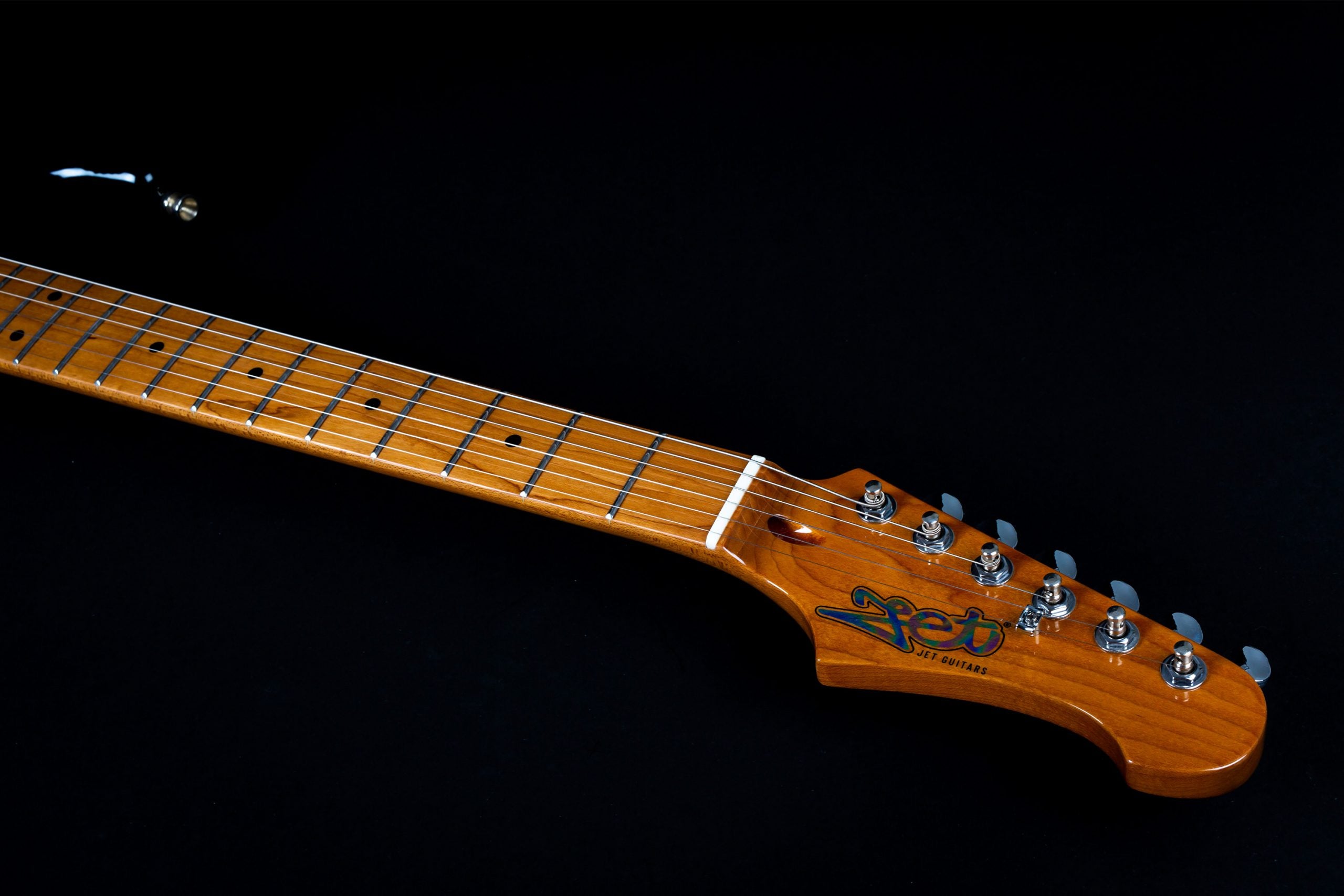 Light brown electric guitar neck and headstock, six metal tuning pegs, dot inlays on the fretboard, Jet Guitars logo on the headstock.