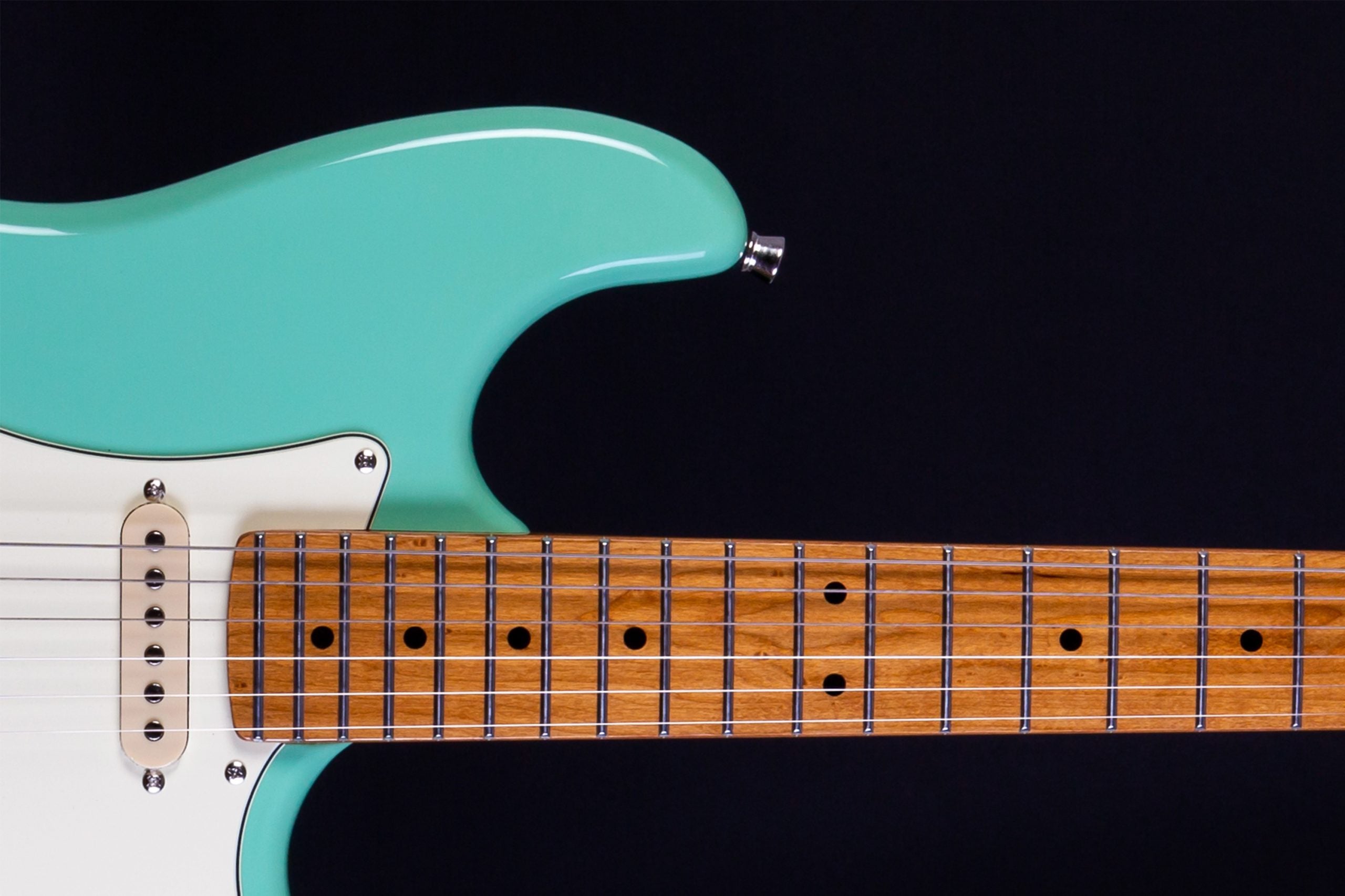 Aqua-colored electric guitar body with white pickguard and six strings, shown with a wooden fretboard and metal frets against a black background.