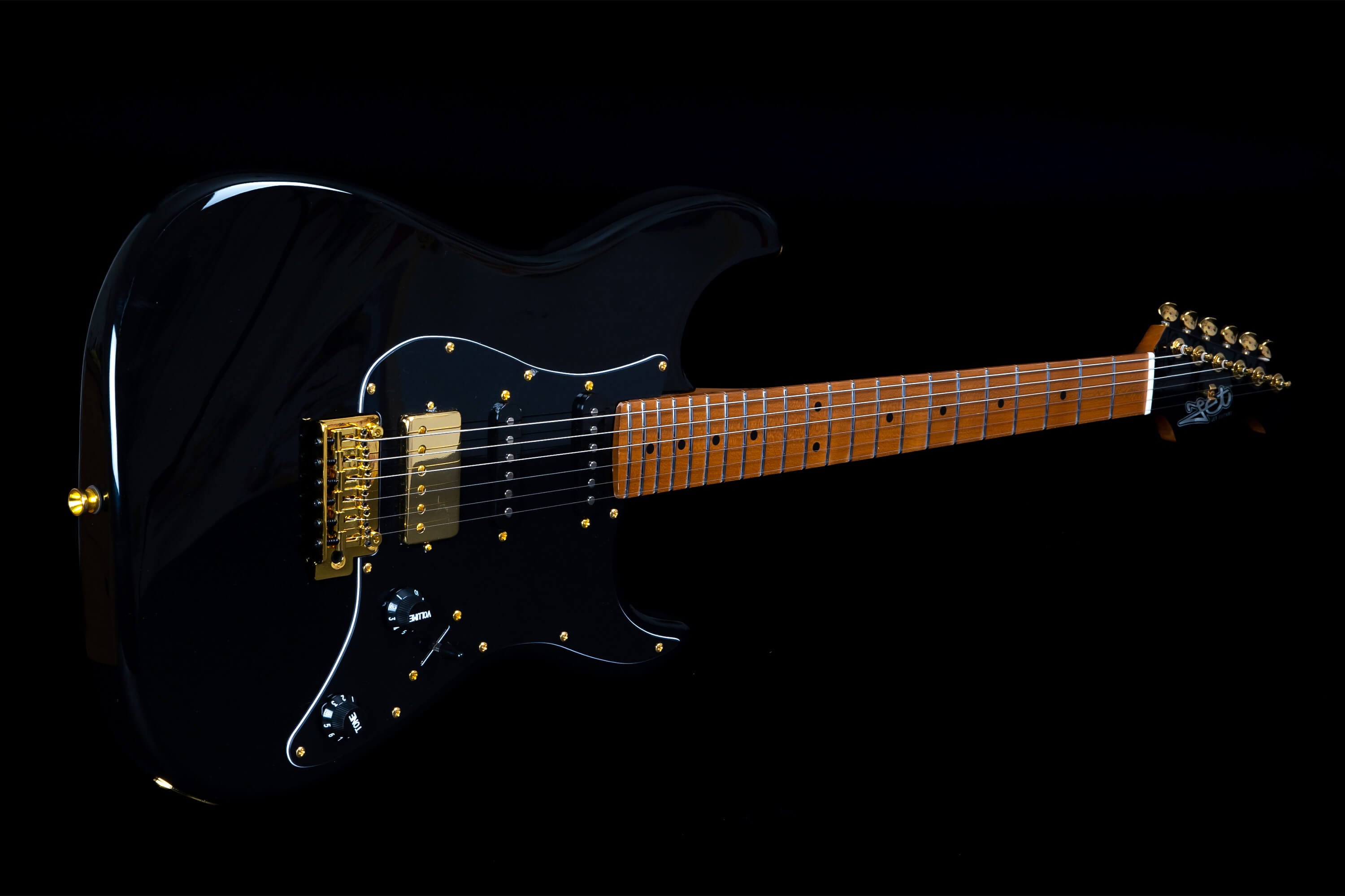 Glossy black electric guitar with gold hardware, black pickguard, two knobs, six strings, and a brown fingerboard with dot inlays.