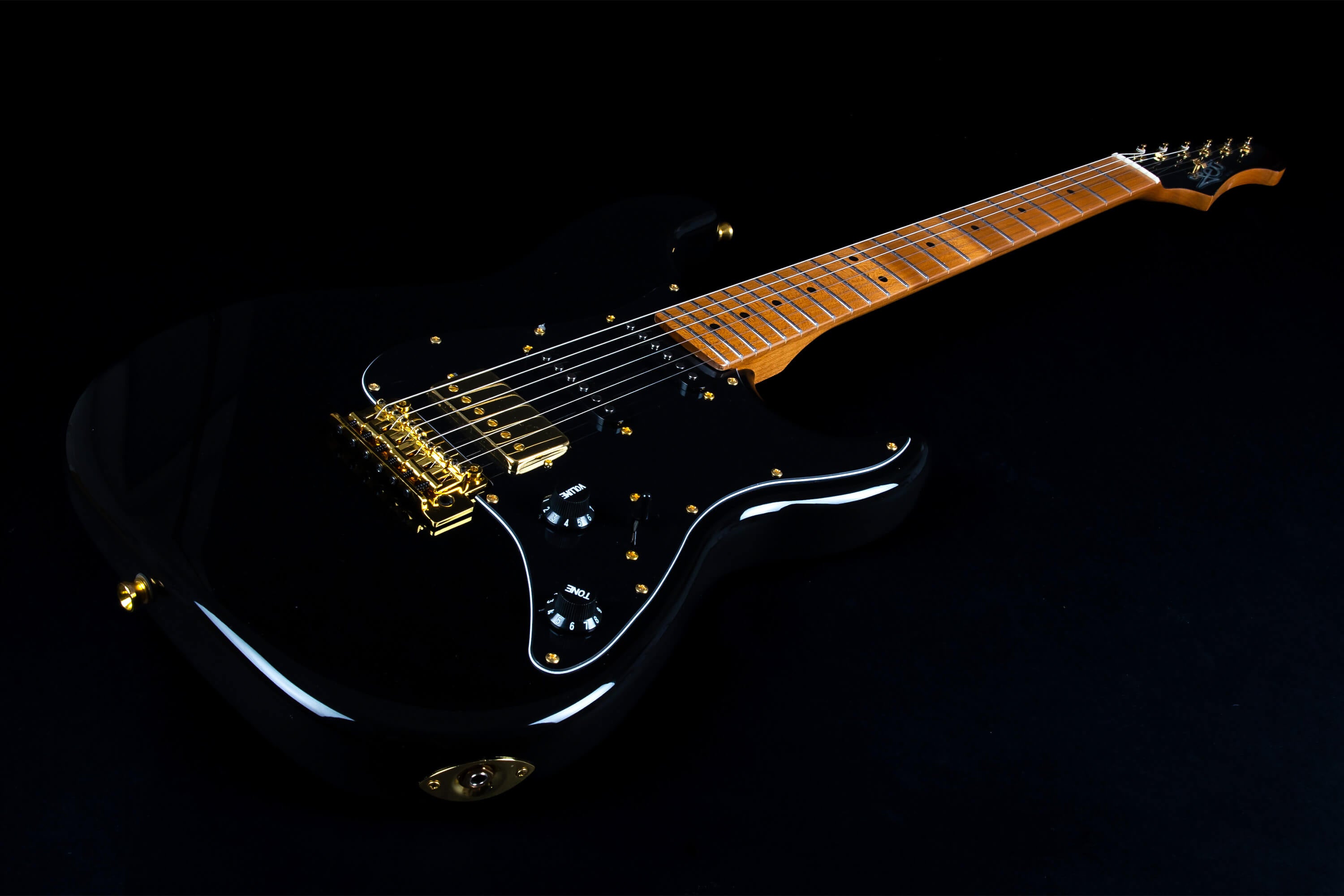 Electric guitar with a glossy black body, gold hardware, black pickguard, black knobs, and a light brown maple fretboard and neck.
