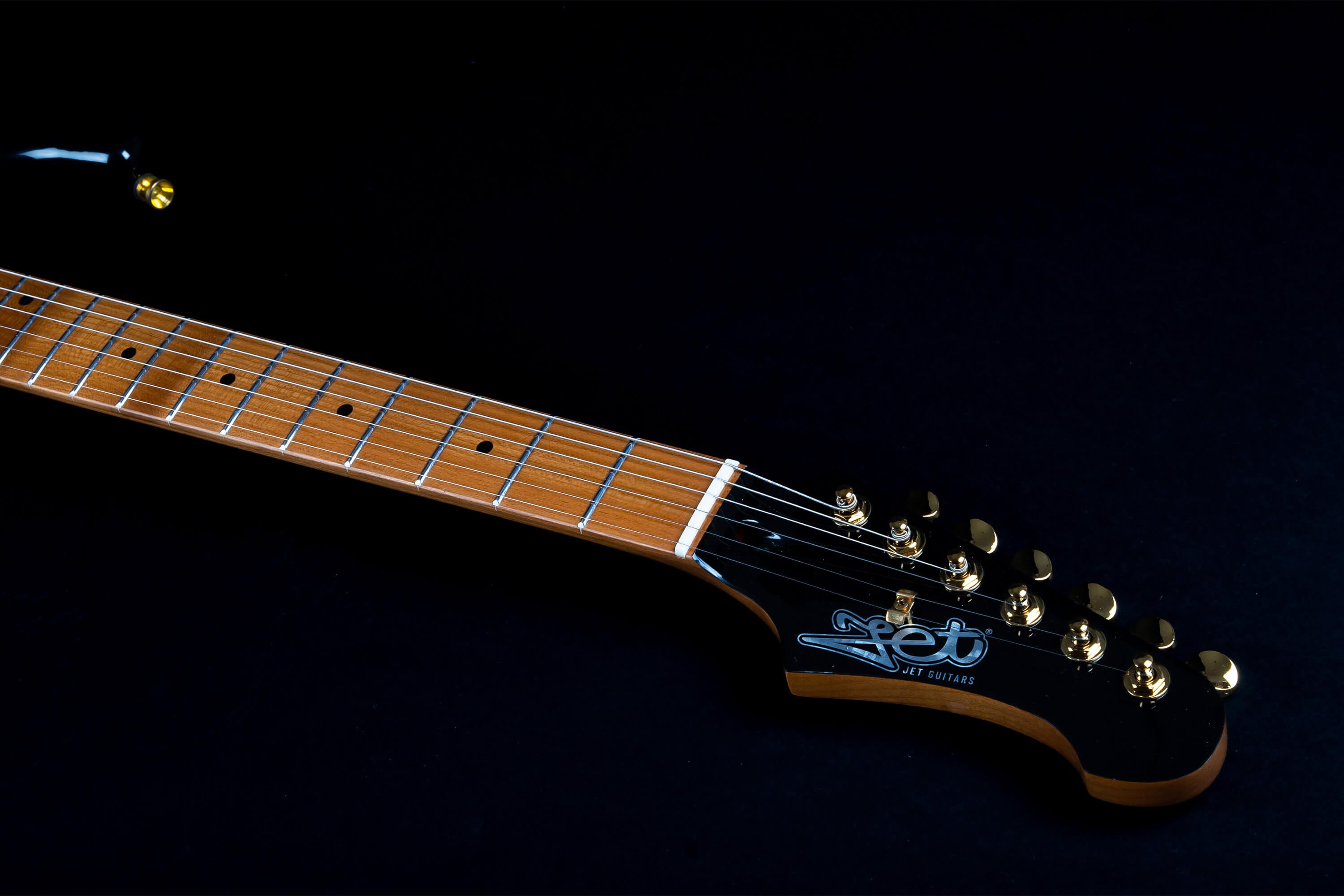 Light brown electric guitar neck and headstock with gold tuning pegs, silver frets, and "Jet Guitars" logo on a black background.