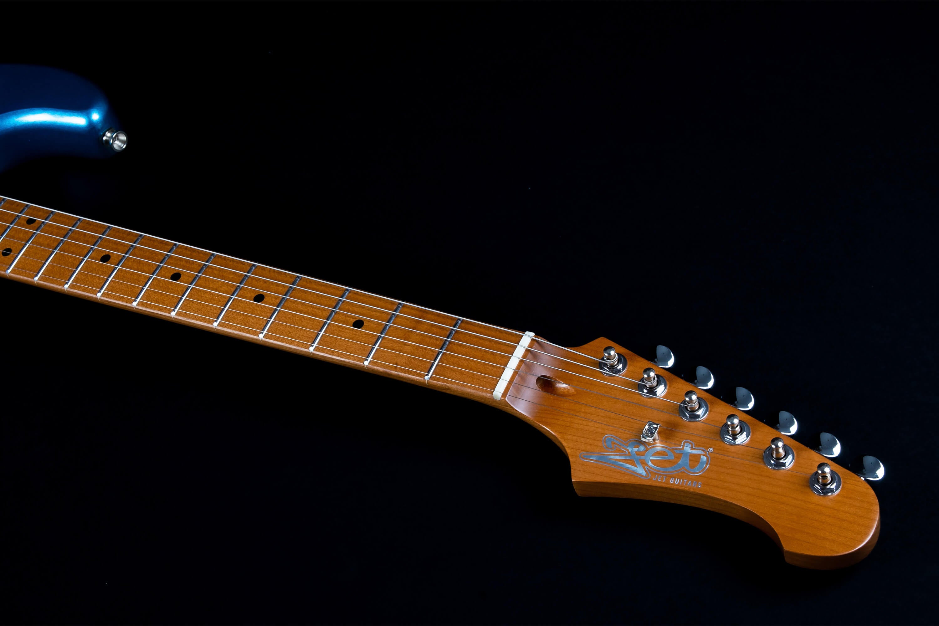 Electric guitar with a glossy blue body, maple neck, six metal tuners, and “Jet Guitars” logo on the wooden headstock.