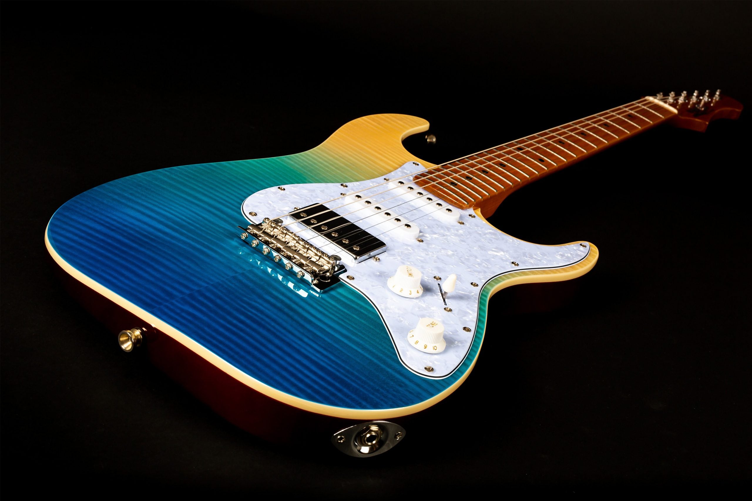 Electric guitar with a glossy flamed top fading from blue to green to yellow, white pickguard, chrome bridge, and control knobs, maple neck and fretboard.