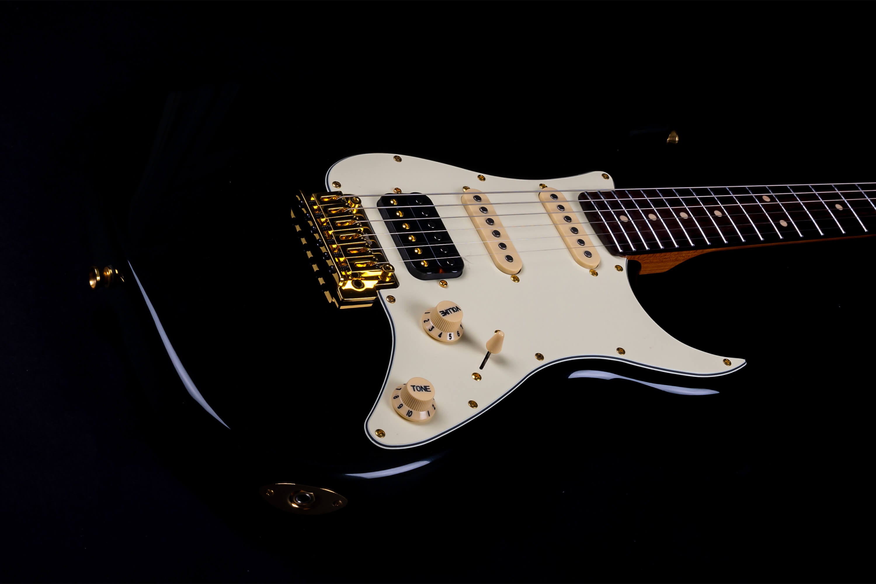 Jet electric guitar with a glossy black body, cream pickguard, gold bridge and hardware, cream knobs, and three single-coil pickups.