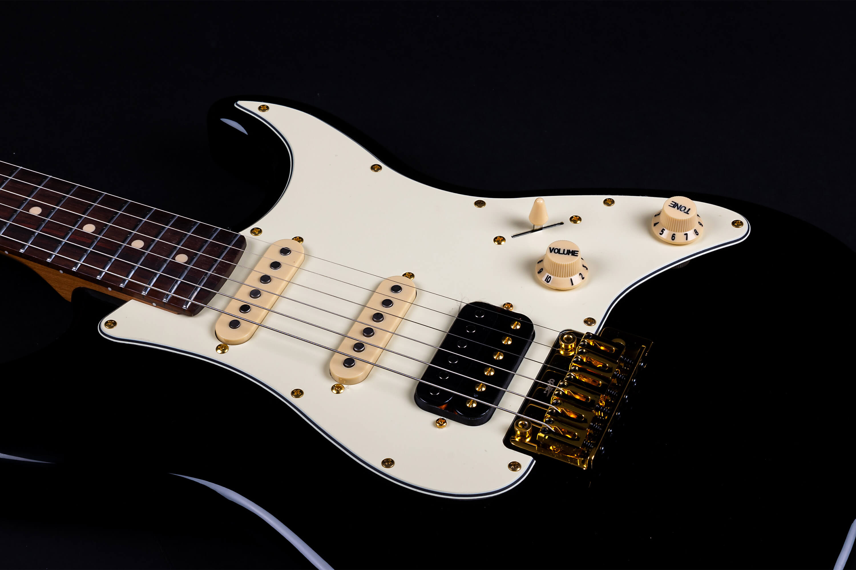 Black Jet electric guitar with a white pickguard, gold bridge, cream knobs, and three pickups, including one black humbucker near the bridge.