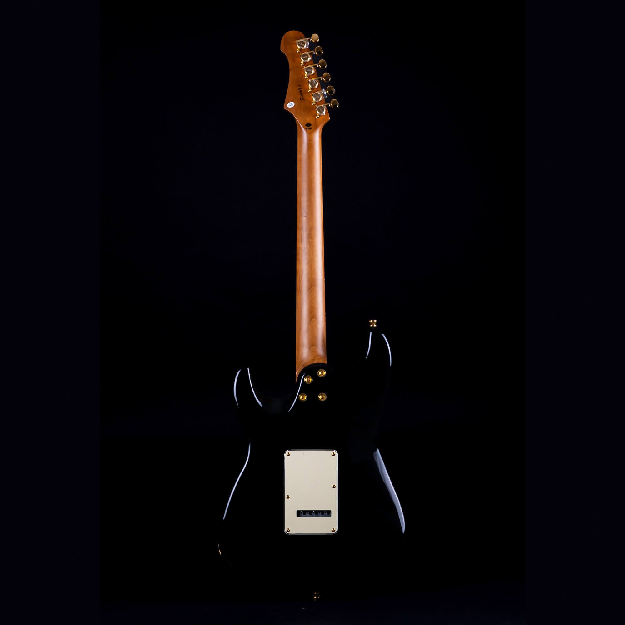 A Jet electric guitar shown from the back, with a natural wood neck, black body, gold tuning pegs, and a white rectangular plate on the body.