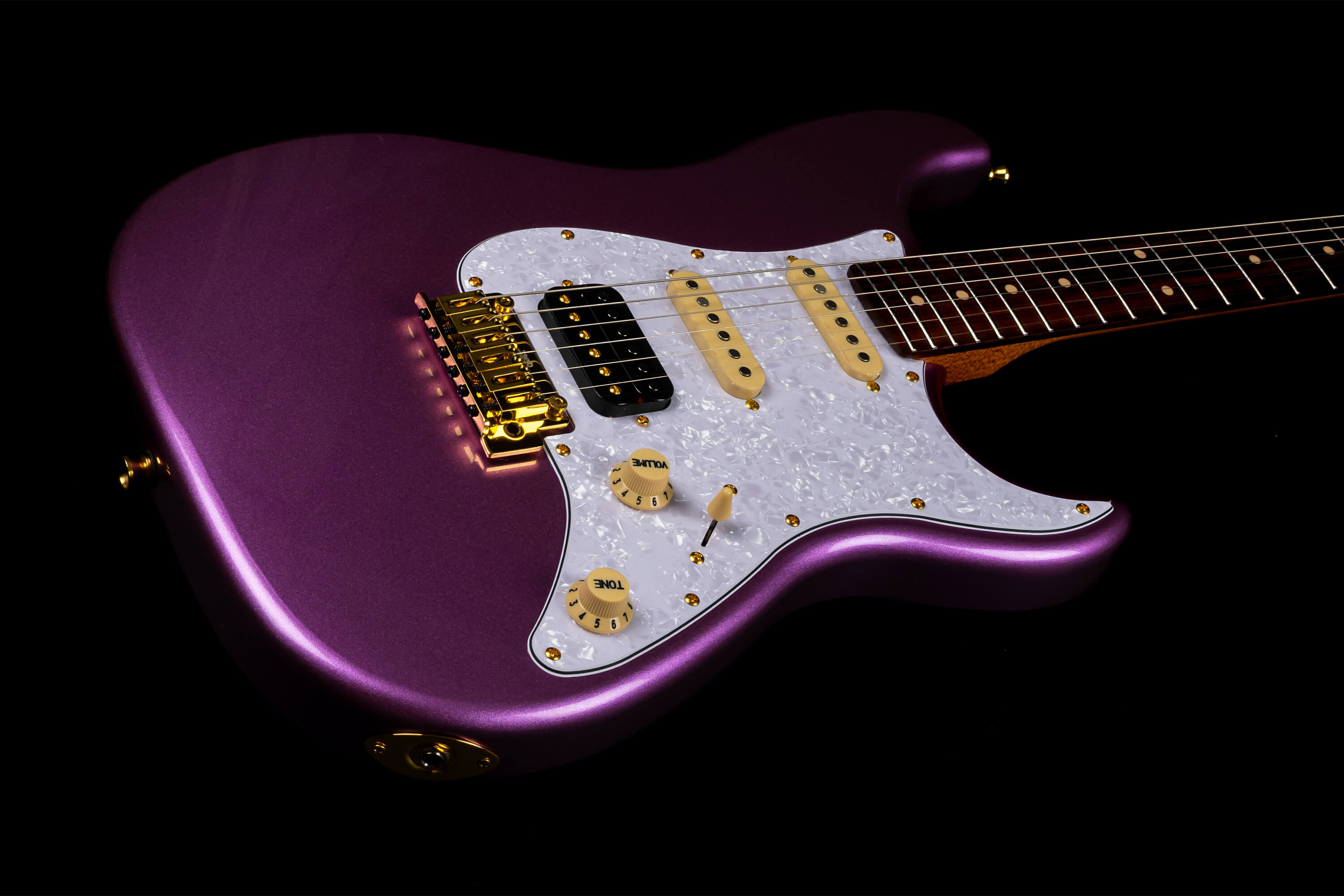 Purple electric guitar with pearl white pickguard, gold hardware, cream knobs, and three single-coil pickups.