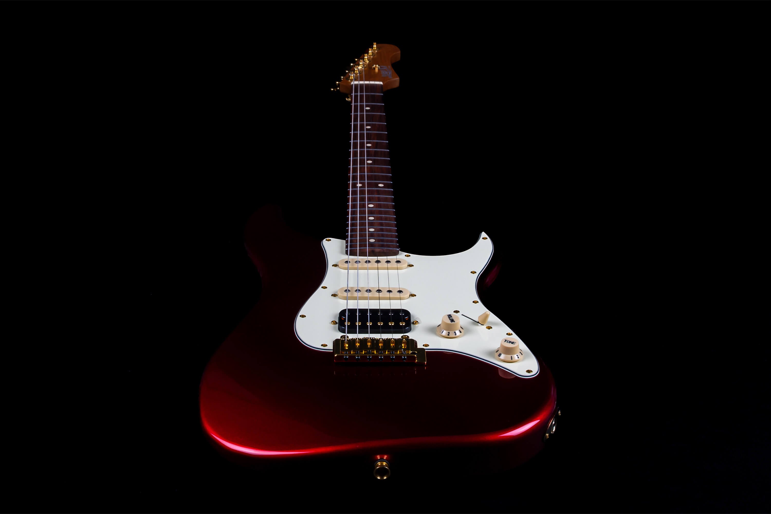 Red electric guitar with a white pickguard, gold hardware, three pickups, and a rosewood fretboard set against a black background.