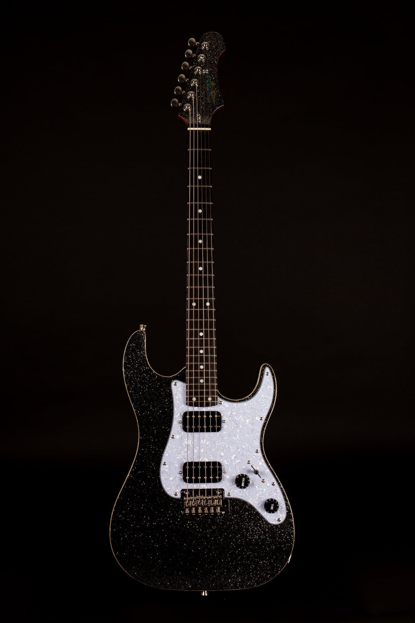 Electric guitar with a black and silver glittery body, white pearloid pickguard, two pickups, and chrome hardware against a dark background.