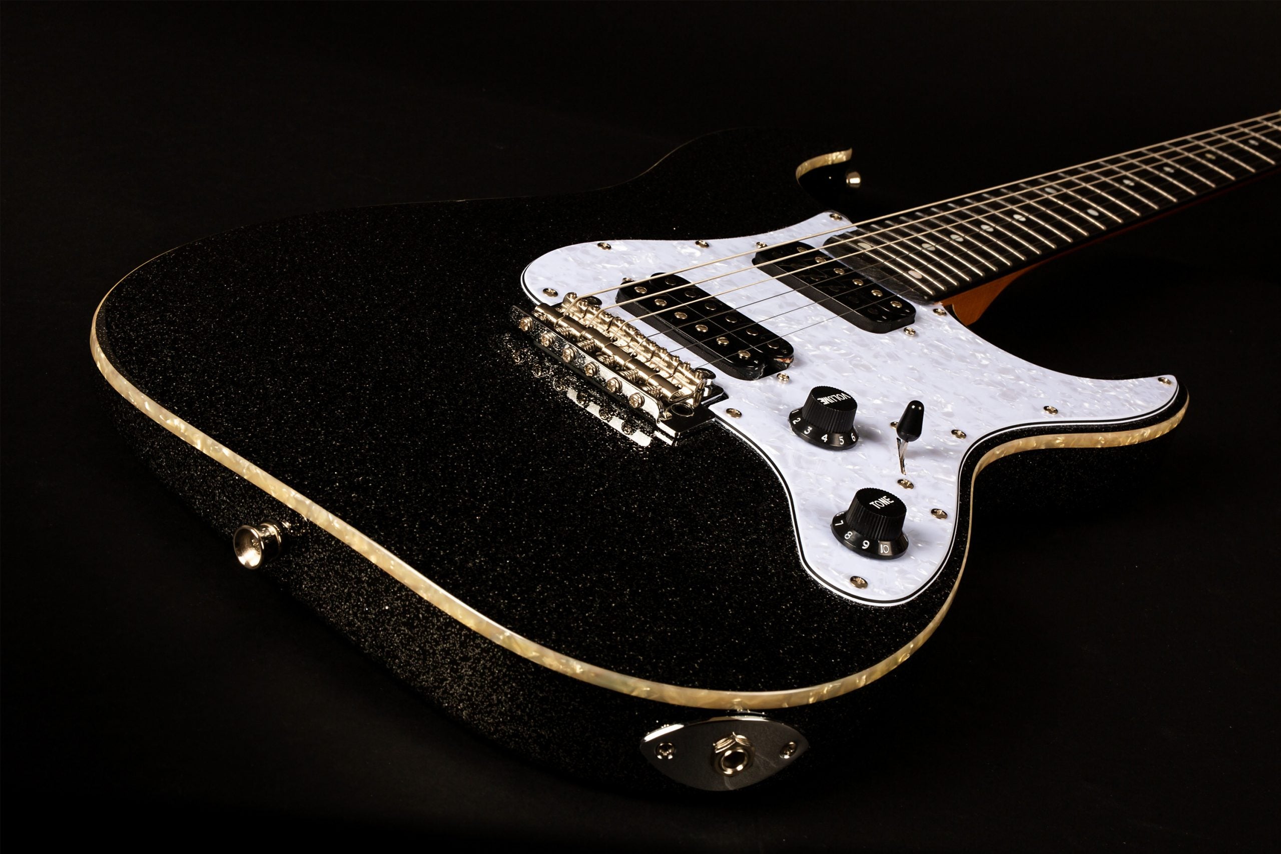Black sparkly electric guitar with a white pearloid pickguard, two black pickups, two black control knobs, and cream binding along the body edge.