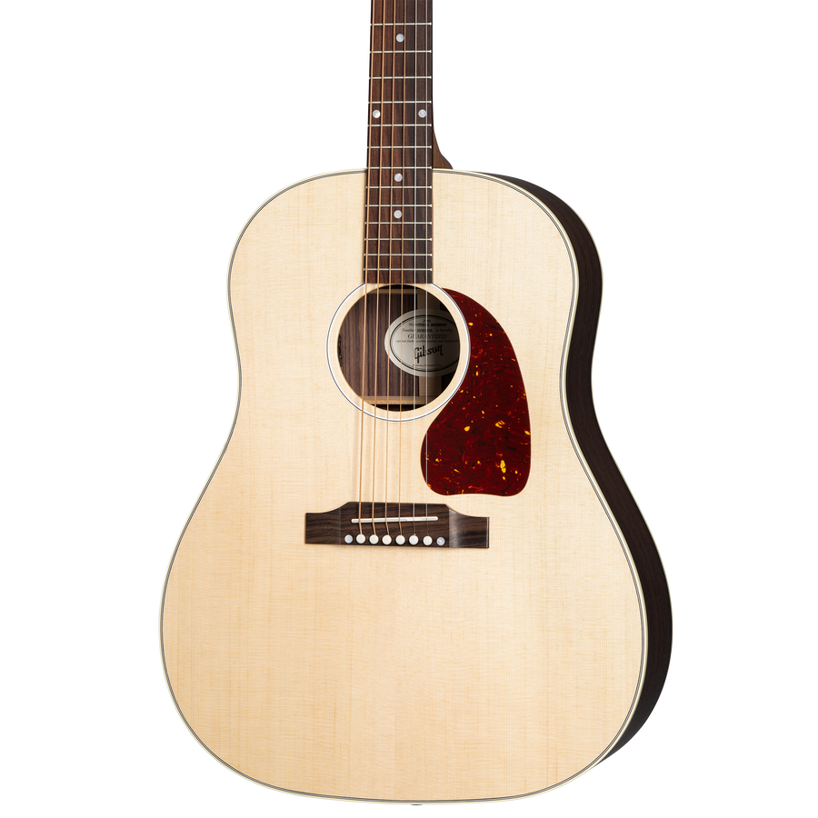 Acoustic guitar with a light wood top, dark sides, six strings, a circular sound hole, and a reddish-brown pickguard beside the strings.