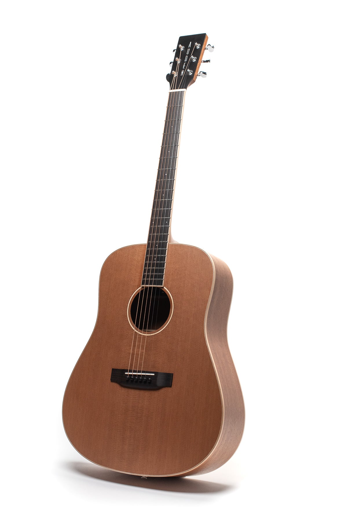 Brown acoustic guitar with a large rounded body, black pickguard, six strings, and a dark fingerboard; tuning pegs are silver metal.