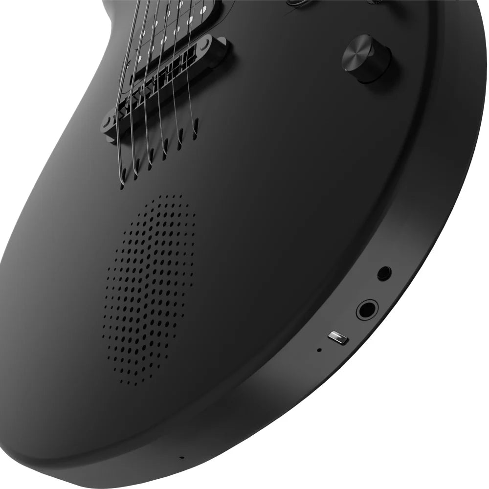 Matte black electric guitar body with built-in speaker, two control knobs, USB-C port, and headphone jack visible near the edge.