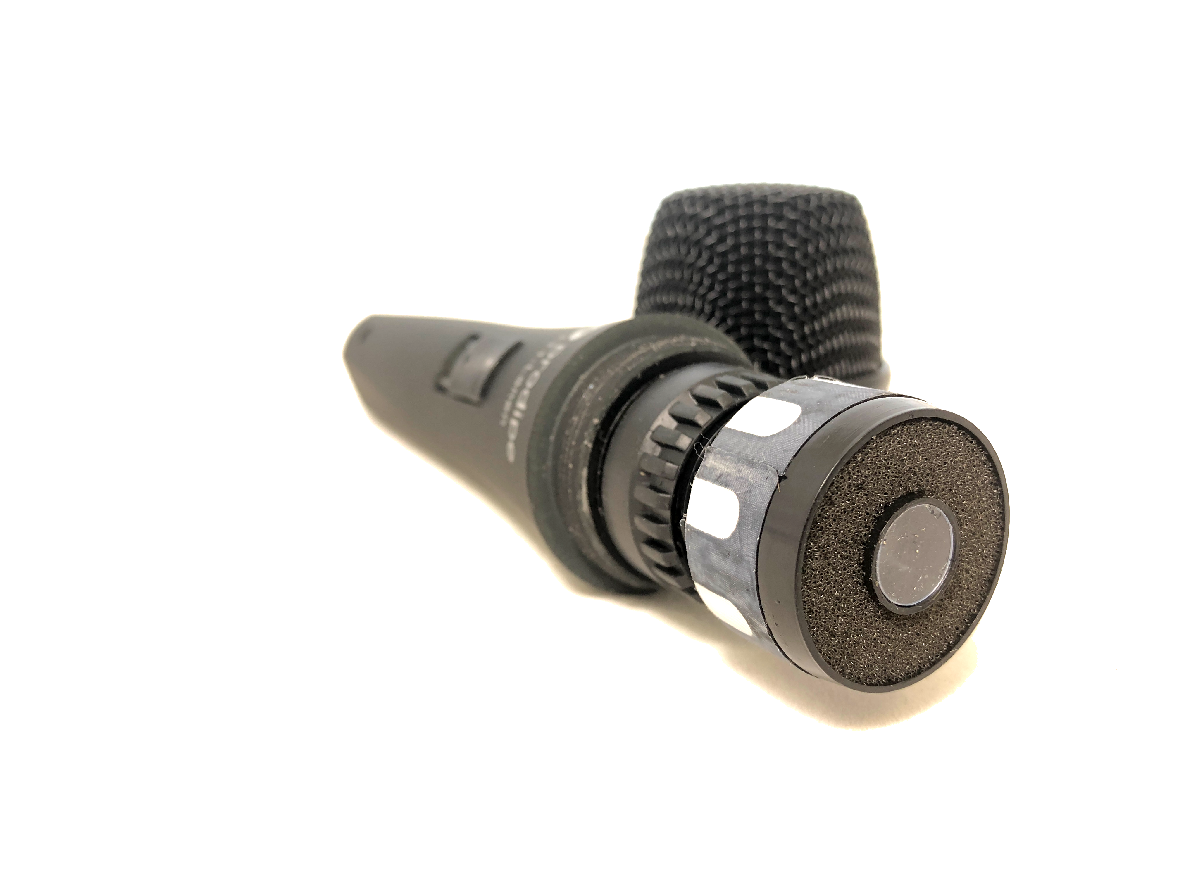 Black handheld microphone with a foam-covered head, on-off switch, and adjustment ring, viewed from the cable connector end.